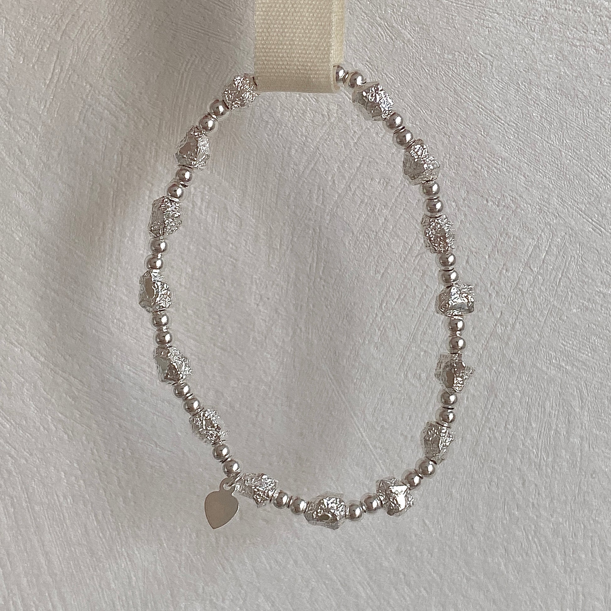 Full isolated view of the handmade sterling silver stretch bracelet with irregular textured beads, 15cm length.