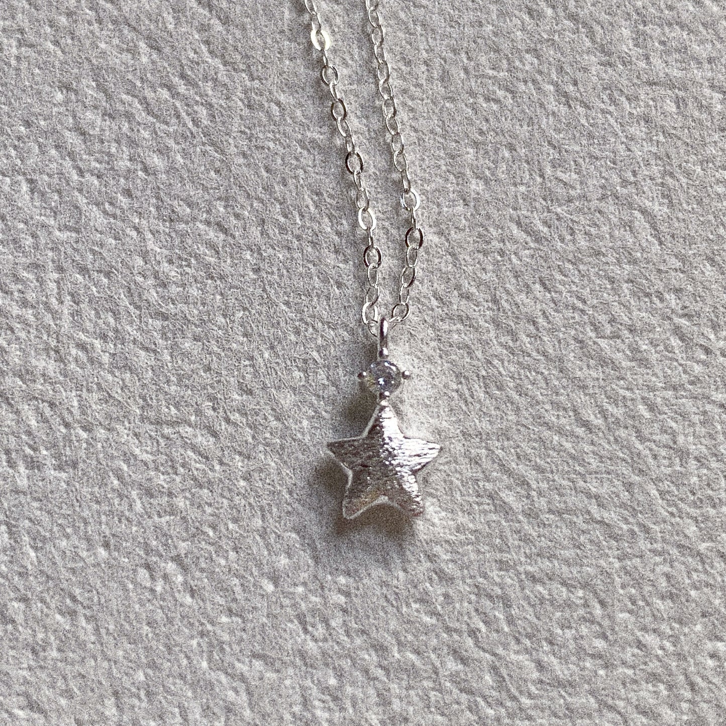Brushed silver star pendant with clear stone detail