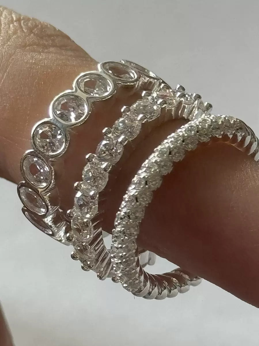Sterling silver rings stacked on finger, high sparkle.