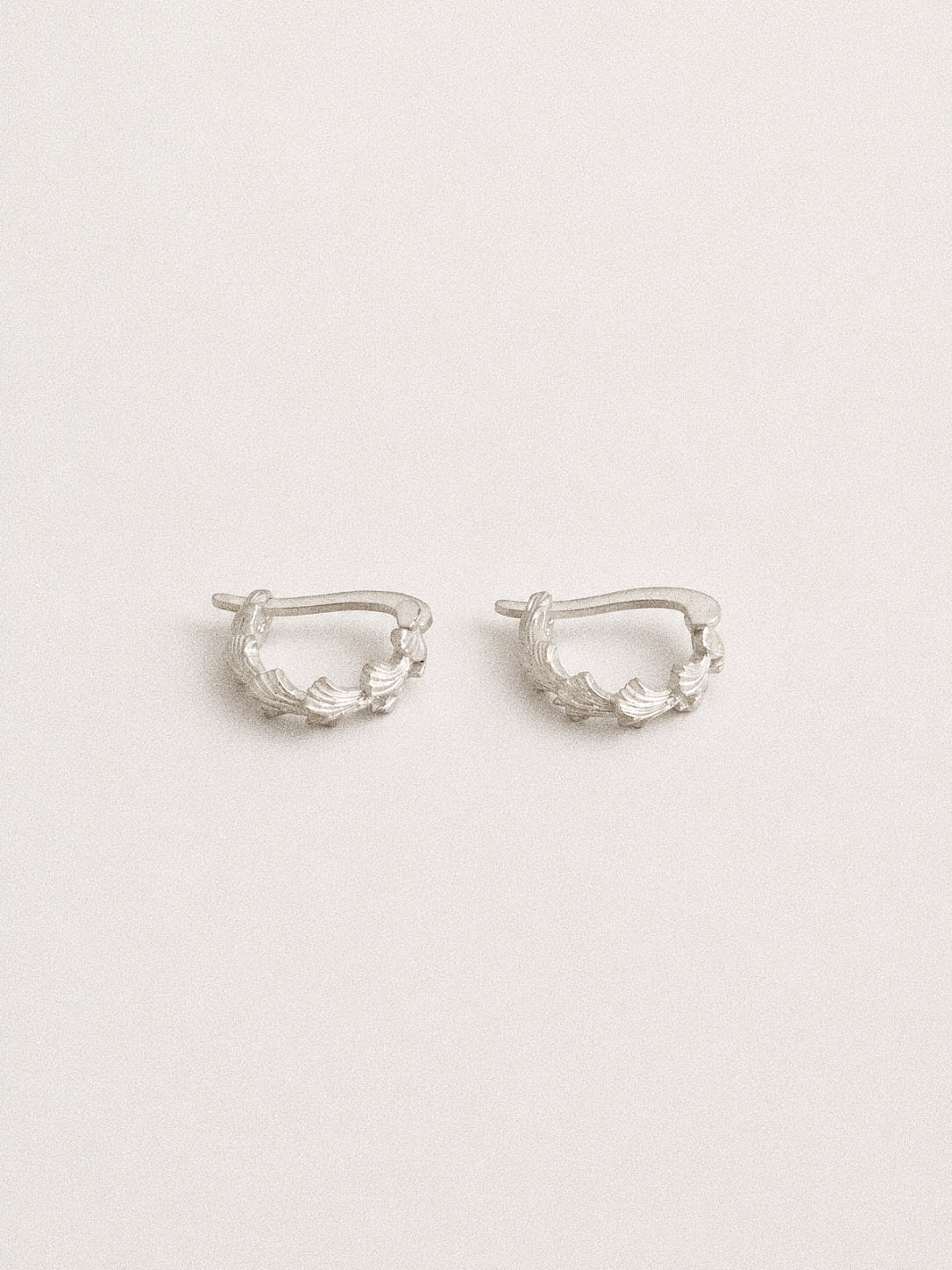 Rear view of the Grove silver leaf huggie earrings showing their compact 10 mm shape and hinged fastening.