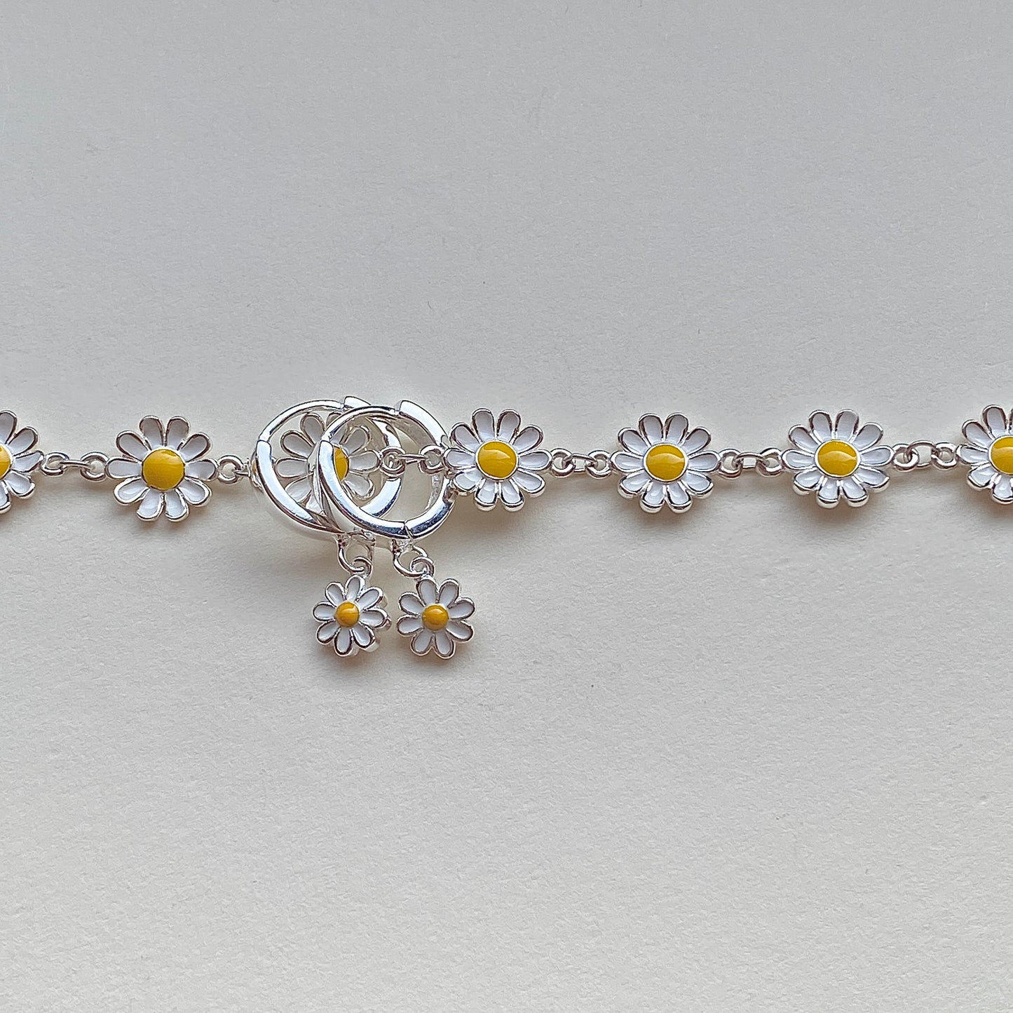 Daisy huggie hoops styled beside matching daisy bracelet