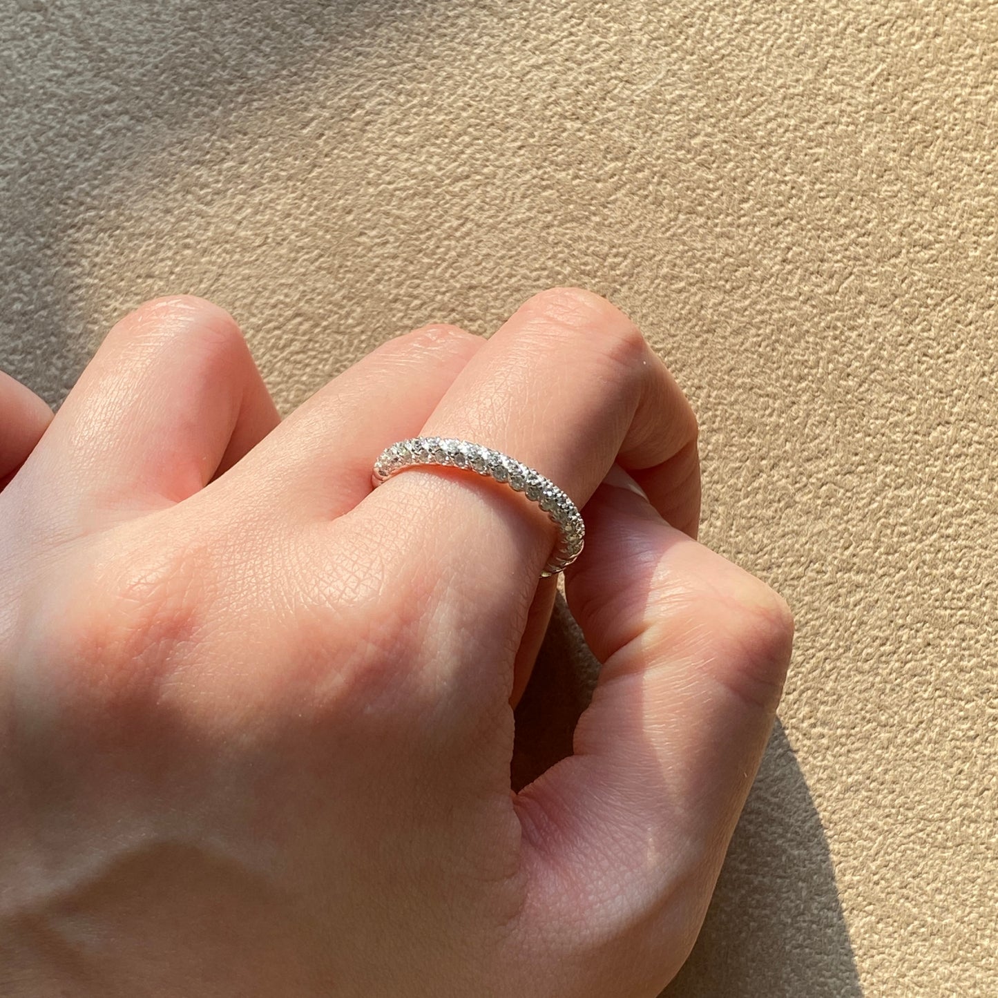 Single sterling silver rope ring on hand in natural sunlight, showing bright micro-stone shimmer.
