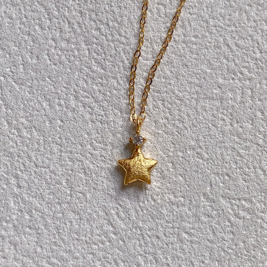 Close up of brushed gold Christmas star necklace with cubic zirconia stone