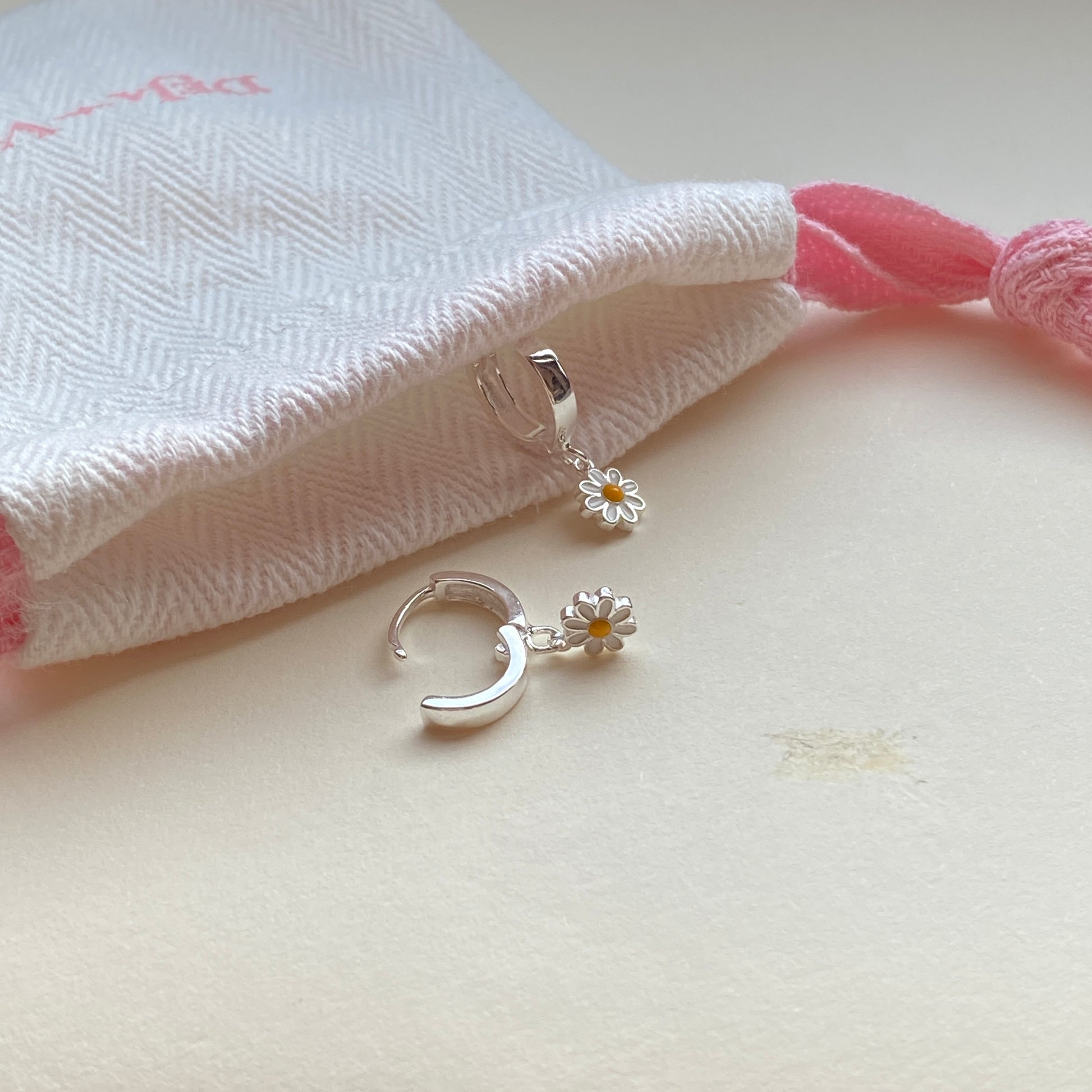 Hinged huggie hoop with detachable double-sided enamel daisy charm