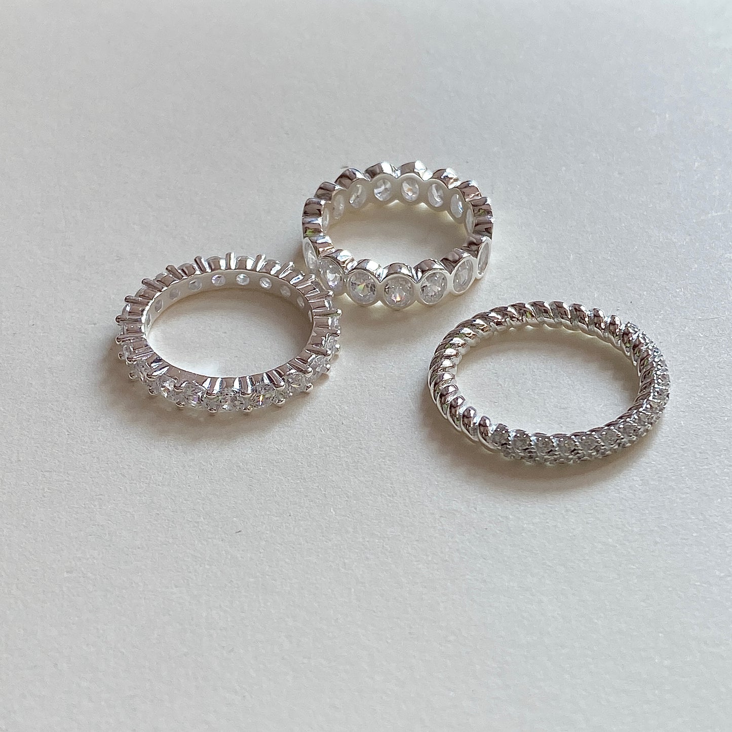 Trio of sterling silver eternity bands—oval bezel, prong set and rope micro-pavé—styled as a stacking ring set for women.