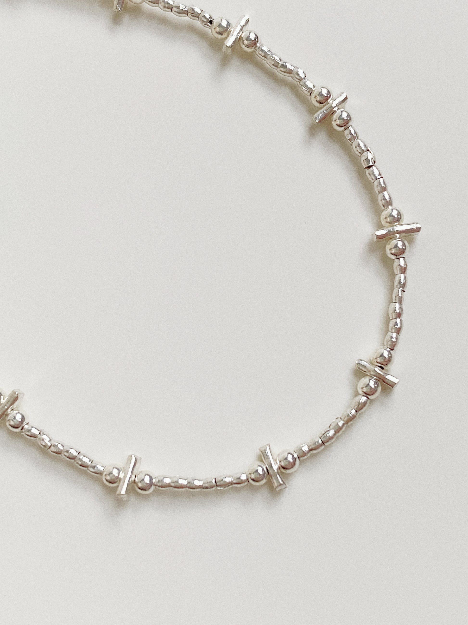 Macro detail shot of the handcrafted silver components and secure connection points of the bar and bead bracelet.