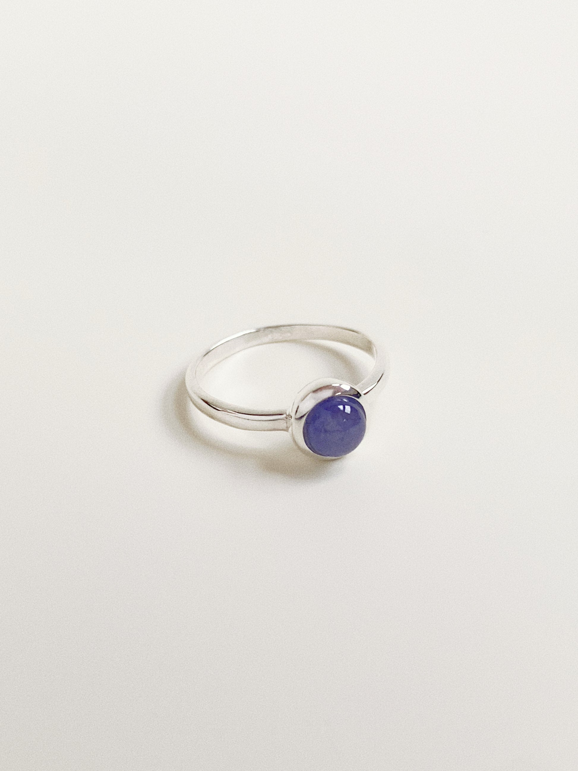 Angled view of the handmade silver gemstone ring, showing the smooth dome shape of the blue tanzanite stone.