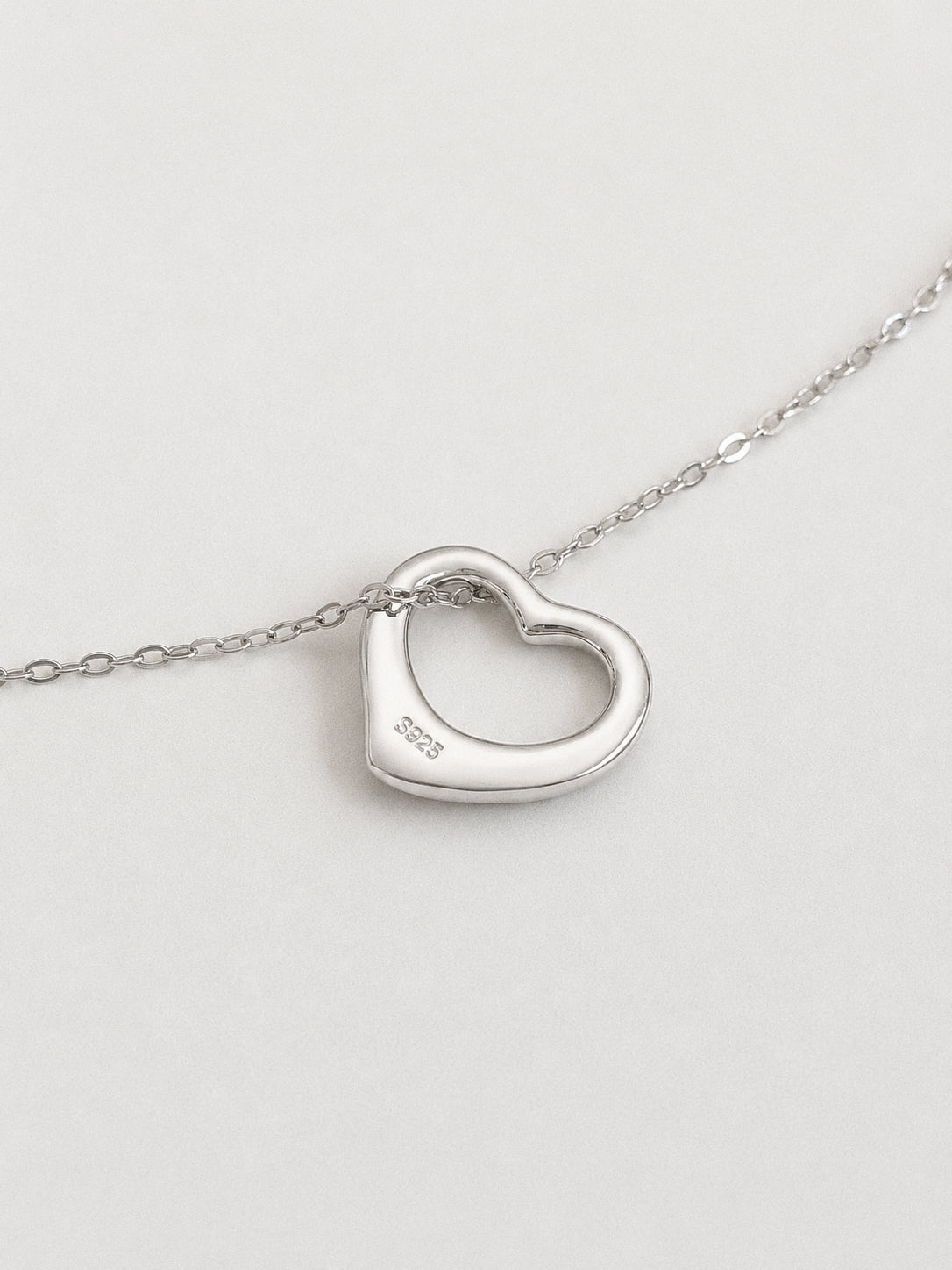 Close-up of a 925 sterling silver open heart pendant showing the S925 hallmark stamp on a fine chain