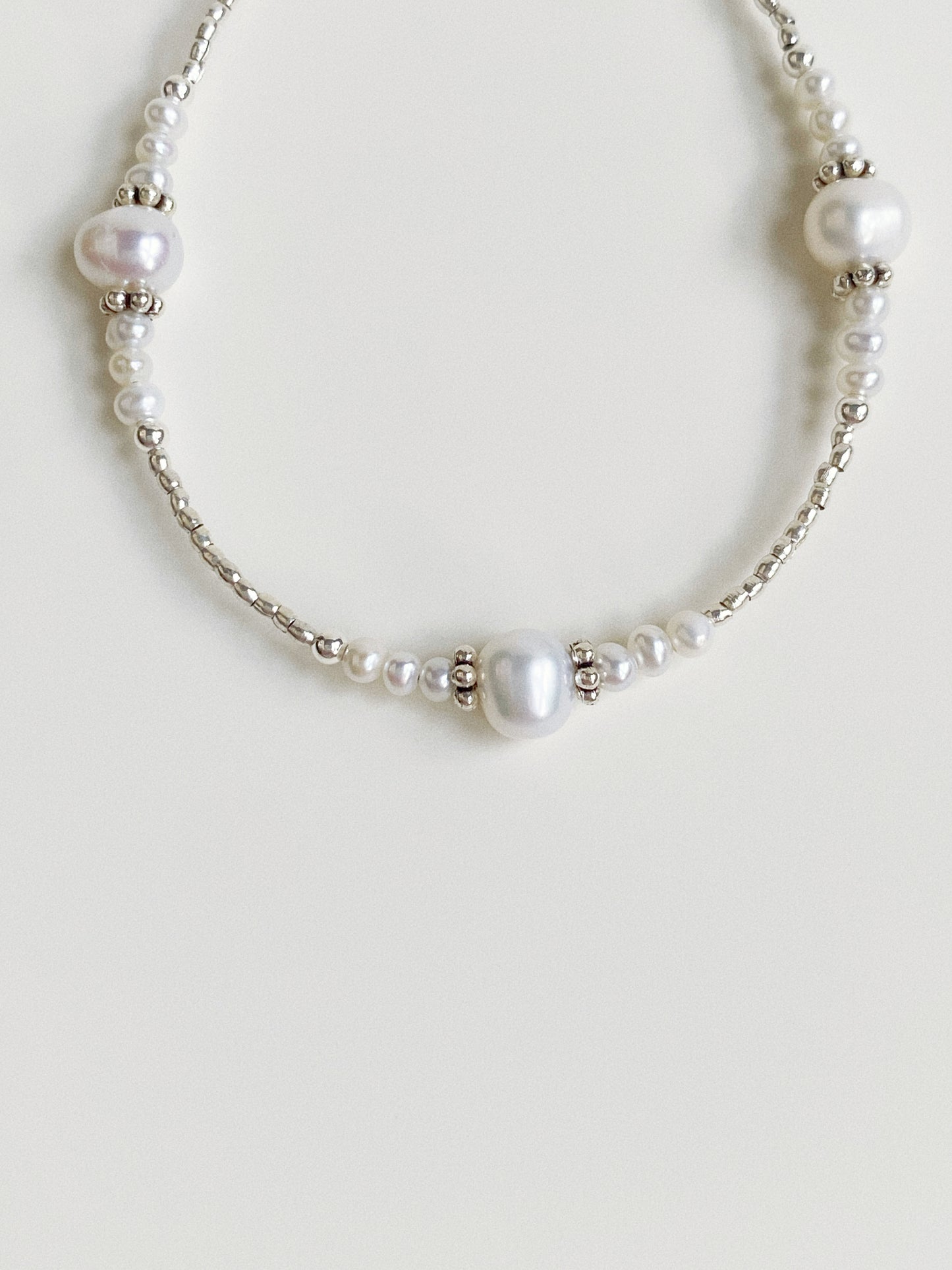 Detailed view of the 925 sterling silver clasp and extension chain on a pearl beaded bracelet.