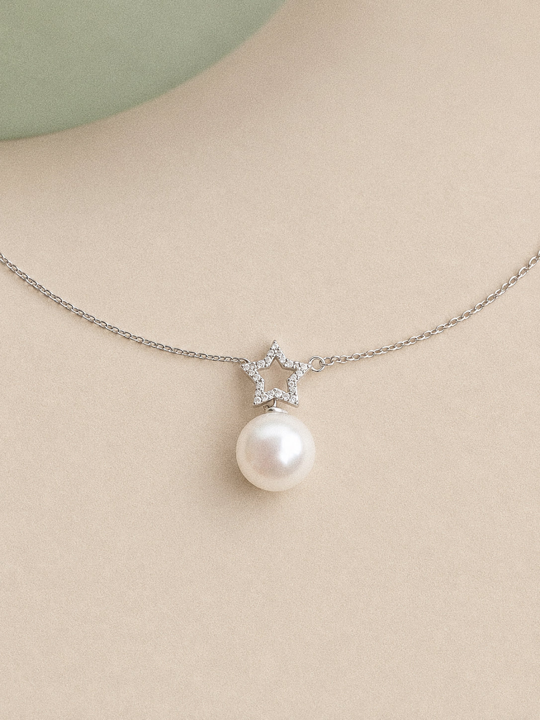 Close view of the sterling silver open star, clear accent stones and high-lustre round Edison pearl.