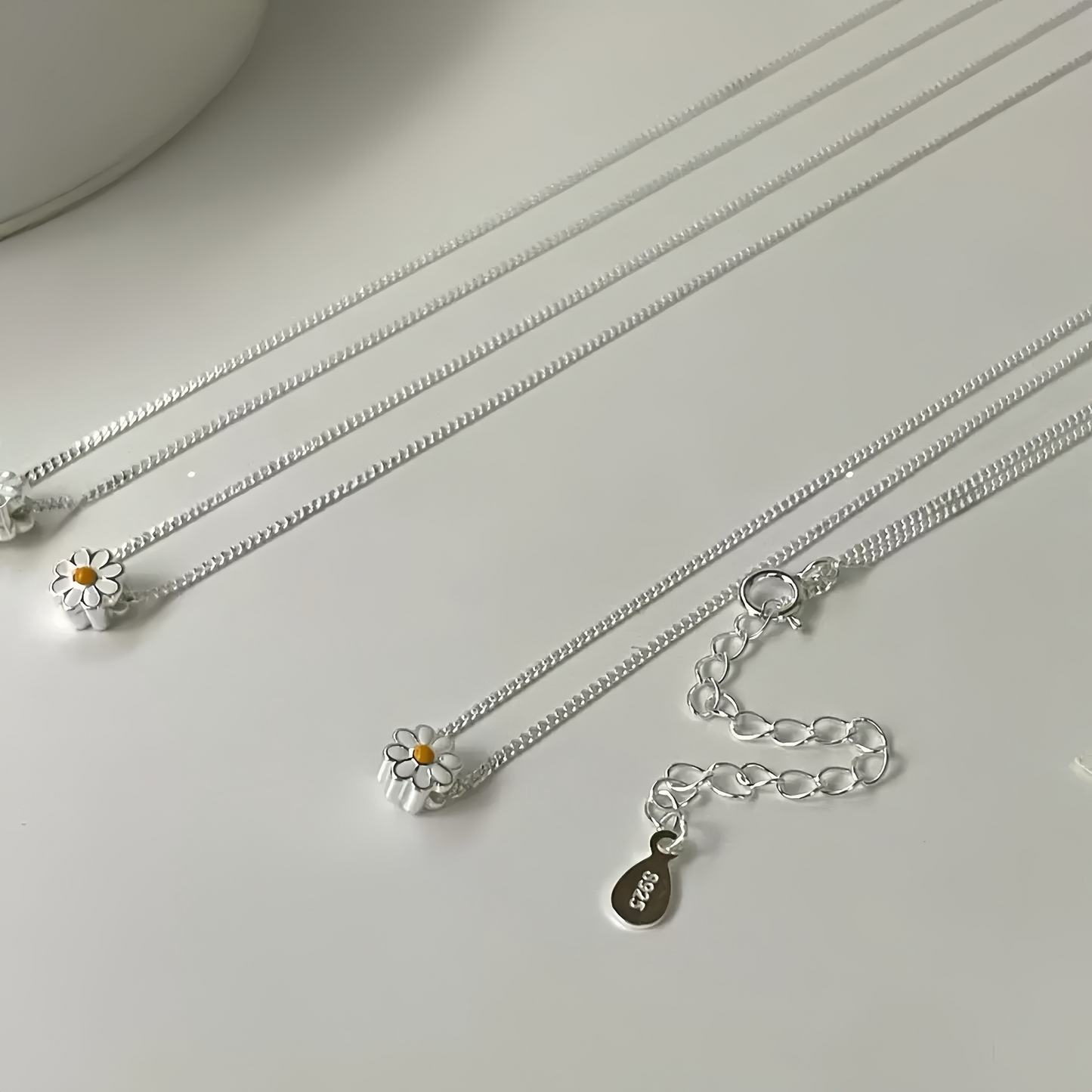 Closeup of double-sided enamel daisy pendant on silver chain