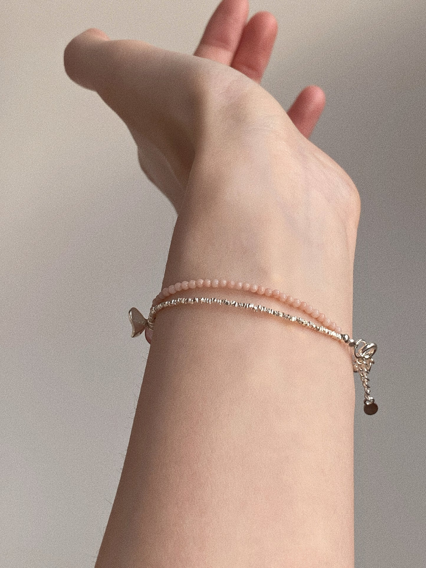 Side view of the double-textured silver and pink gemstone bracelet showing its elegant structured drape.