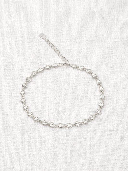 Dainty 925 sterling silver bracelet made of tiny linked puffed love hearts with an extender chain on a white linen background