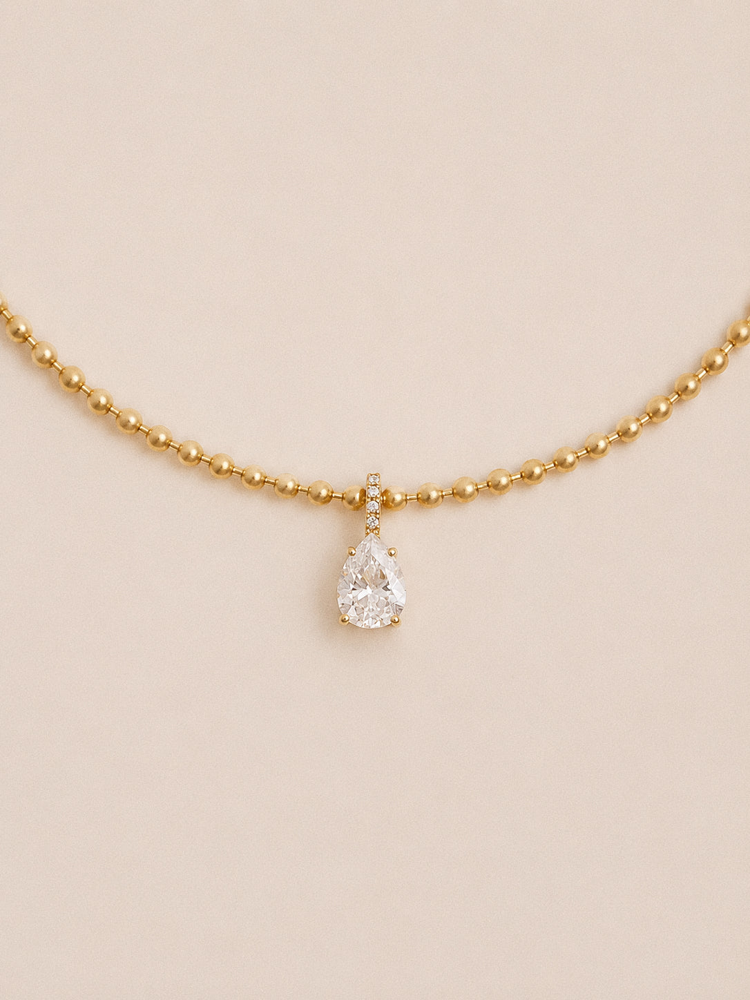 Dew teardrop necklace with pear cut cubic zirconia and pavé bail on a polished gold ball chain