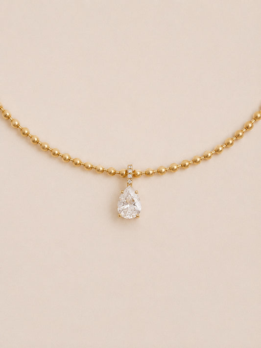 Dew teardrop necklace with pear cut cubic zirconia and pavé bail on a polished gold ball chain