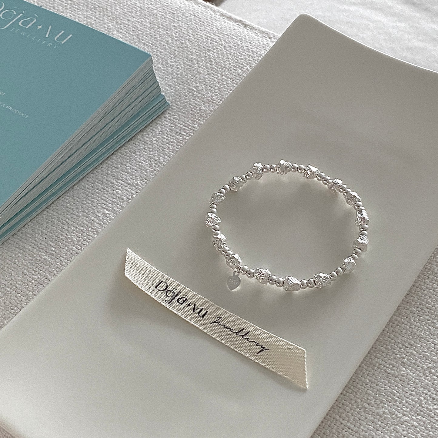 Heavyweight solid 925 sterling silver beaded bracelet styled on a white plate with Deja Vu ribbon, showing luxury texture.