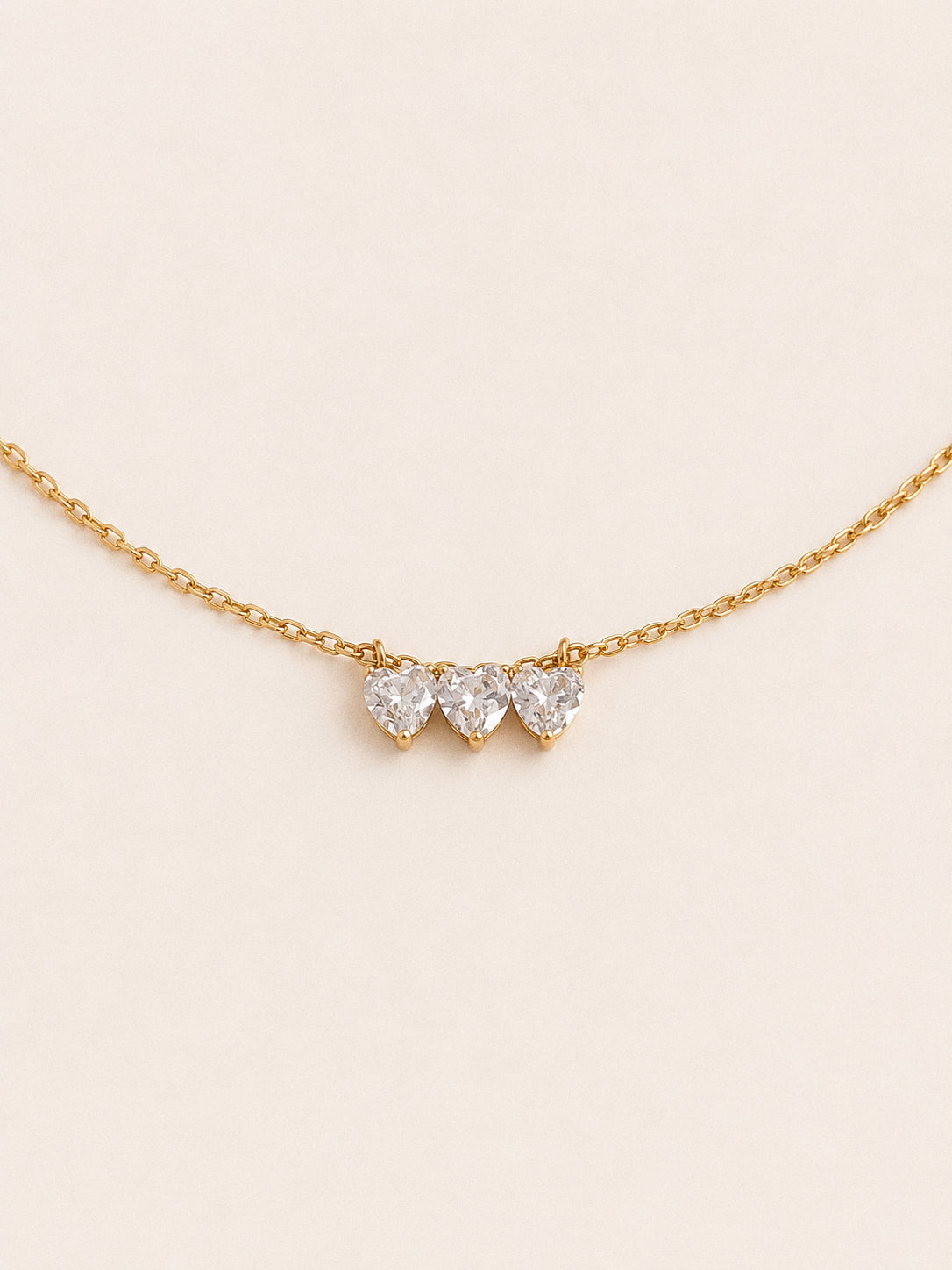 Trio three heart necklace with claw set cubic zirconia hearts in a row on a fine 18k gold chain