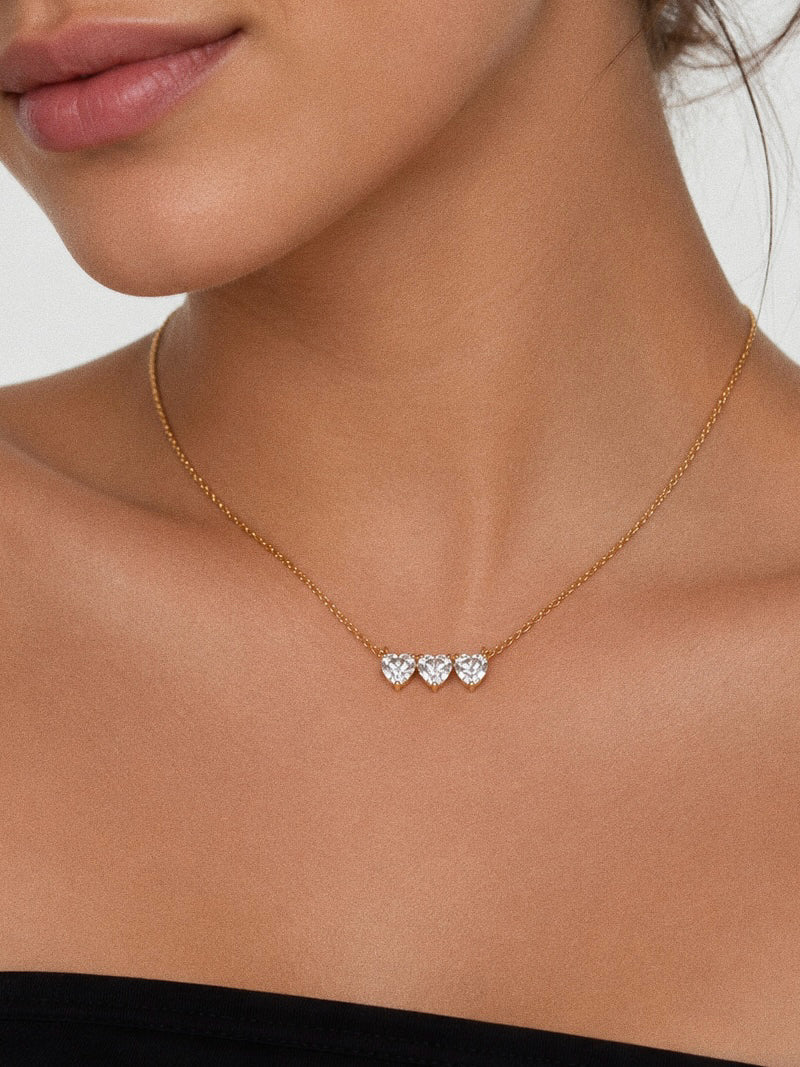 Model wearing the Trio three heart cz necklace sitting at the collarbone in 18k gold