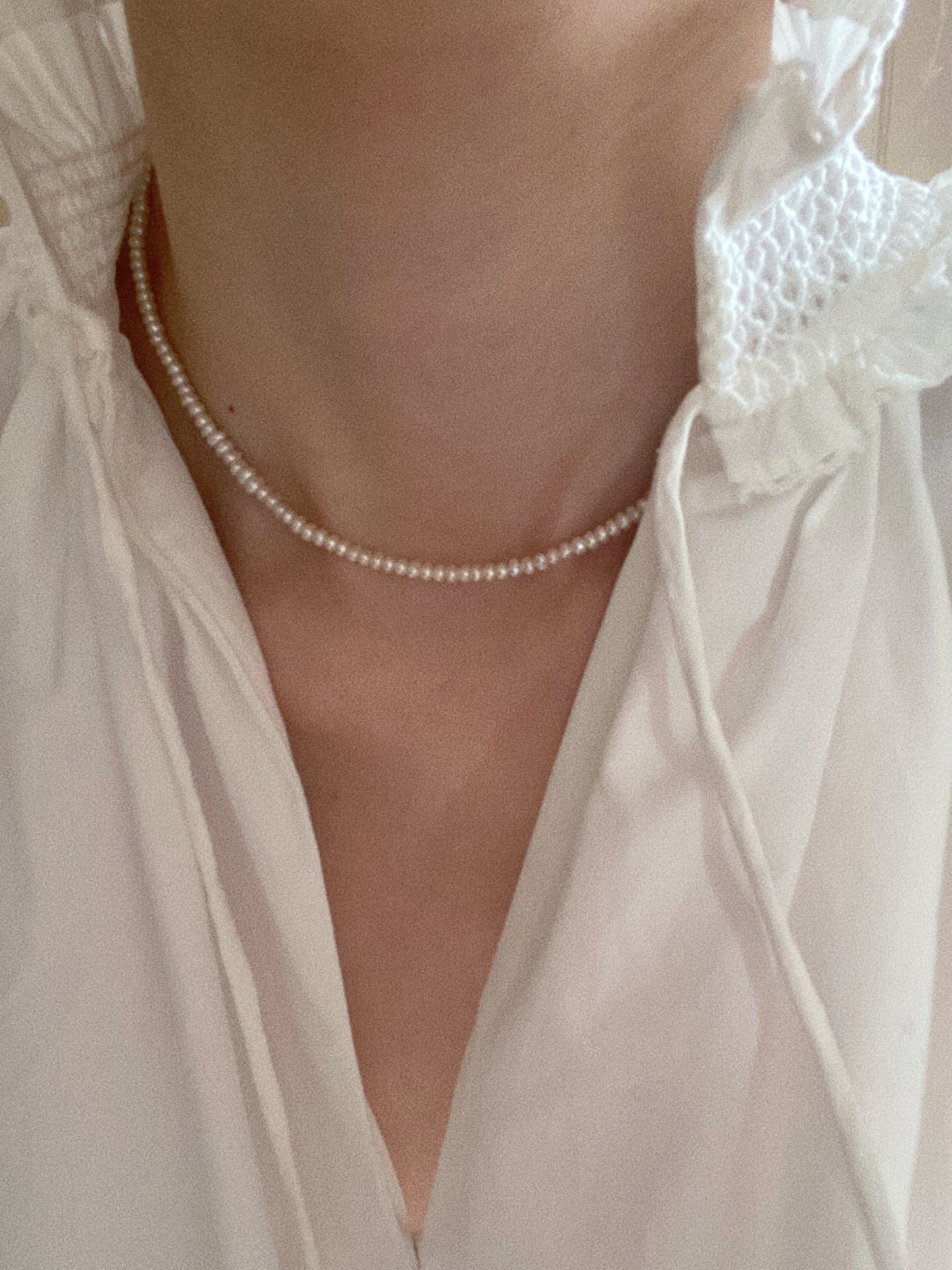 Dainty tiny pearl choker styled on model in white blouse for soft minimalist look