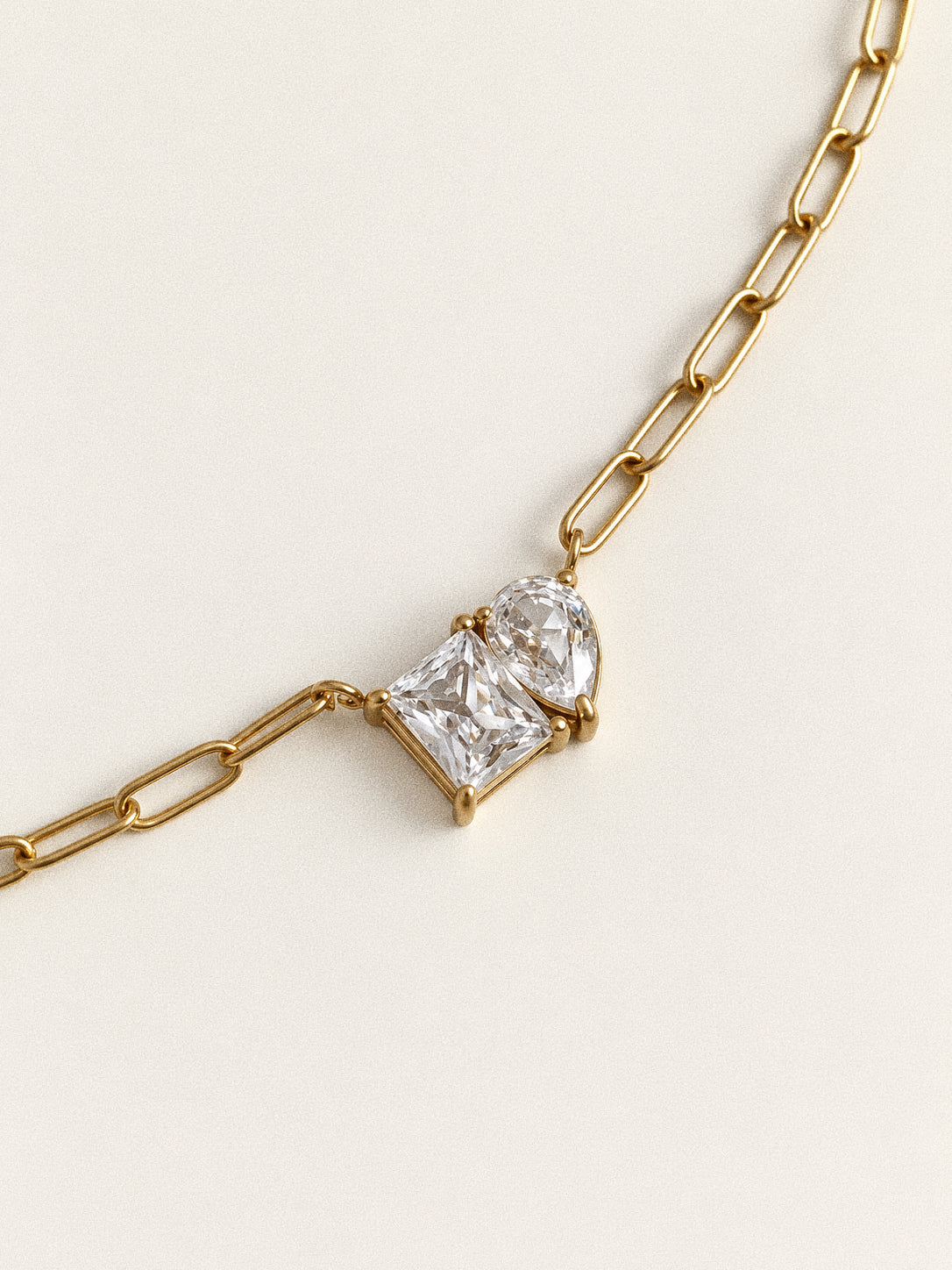 Close-up of the rectangular and pear-shaped stones and gold prong settings on the Toi et Moi necklace.