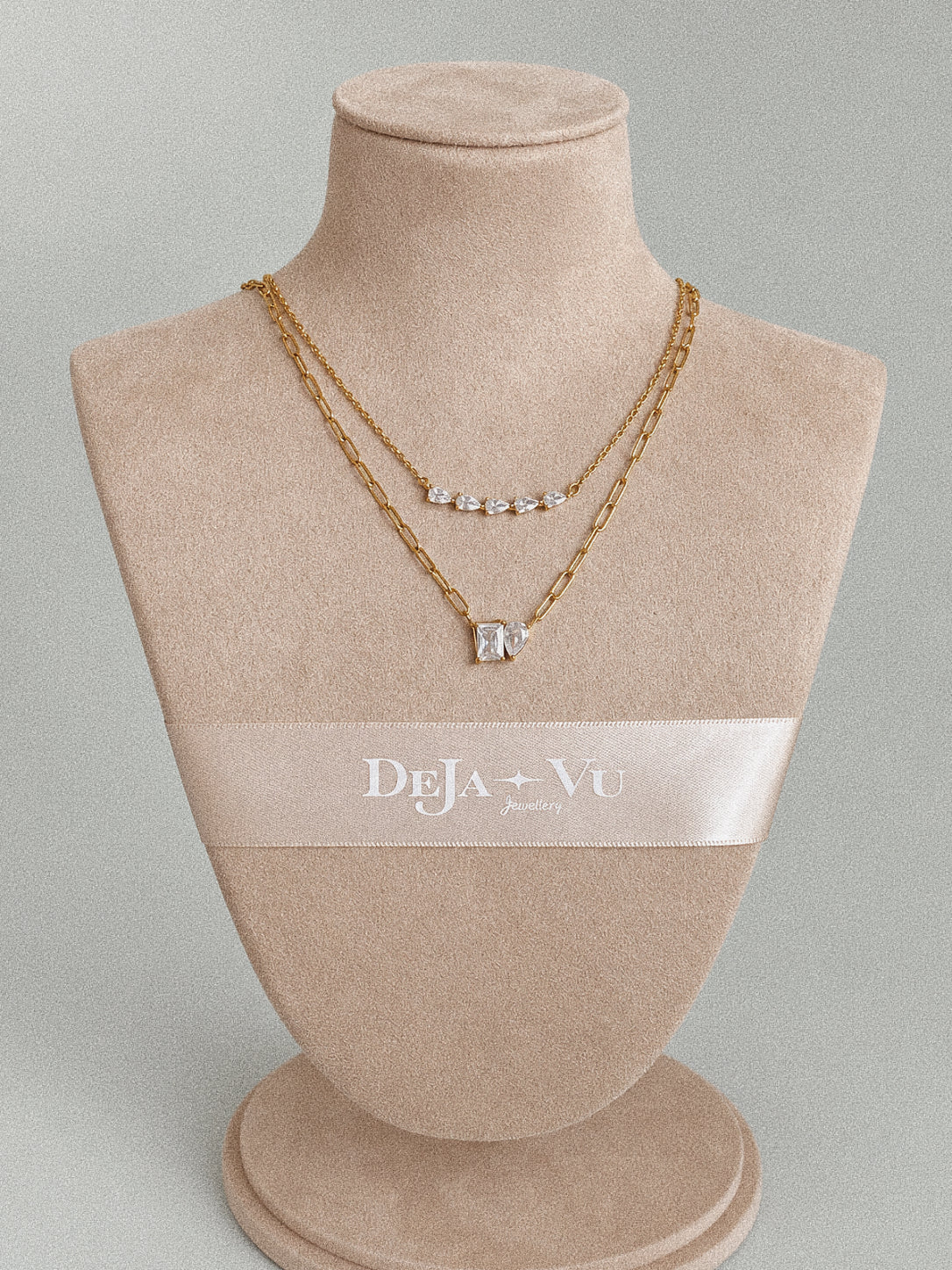 Full view of a beige jewellery stand with the Toi et Moi paperclip necklace layered beneath a shorter necklace.