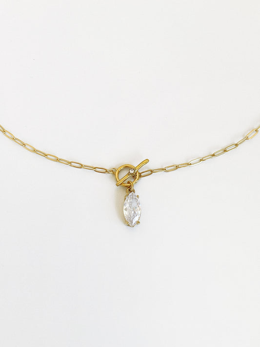 Close-up of the front toggle clasp and dangling marquise zircon drop on a fine gold paperclip chain