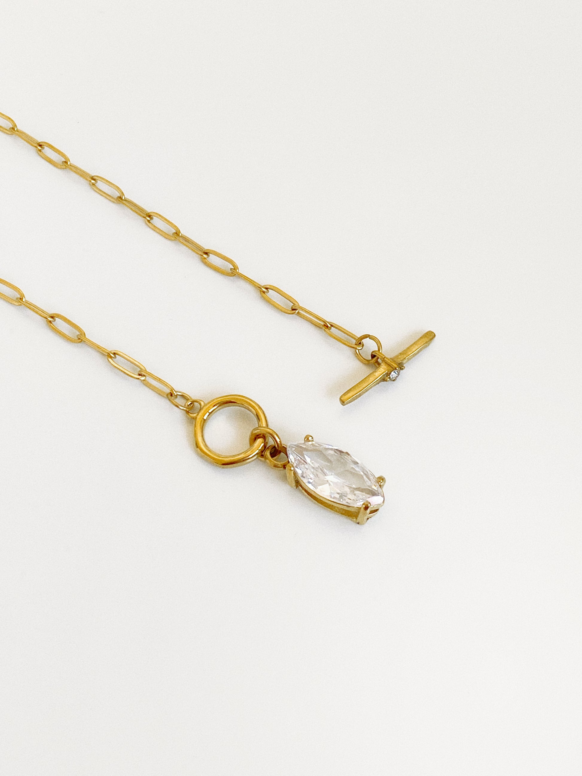 Angled detail of the gold T-bar toggle with a tiny set crystal and the prong-set marquise cubic zirconia drop