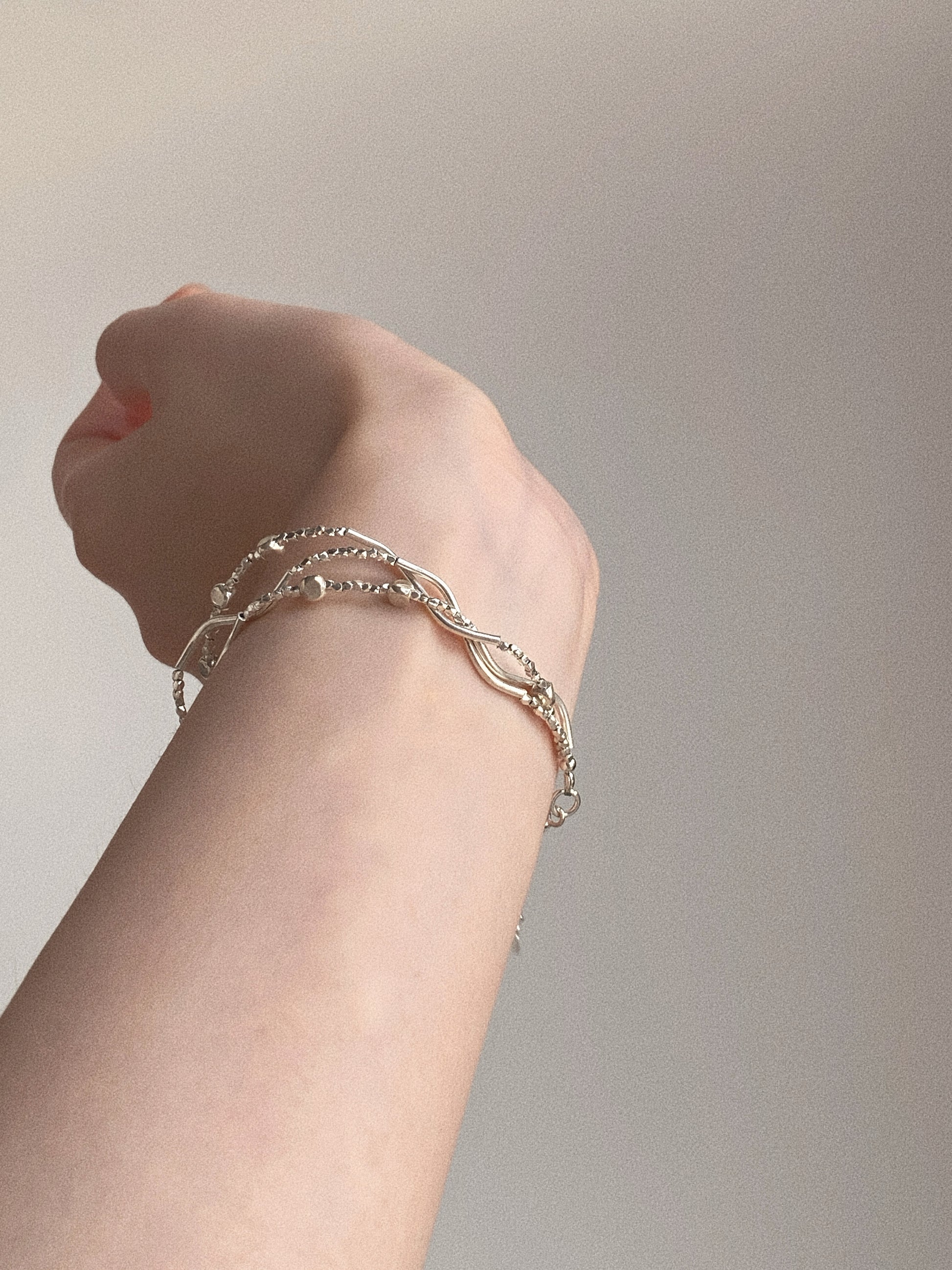 Triple-layer 925 sterling silver bracelet worn on wrist showing handmade wave bar and beaded chain layering