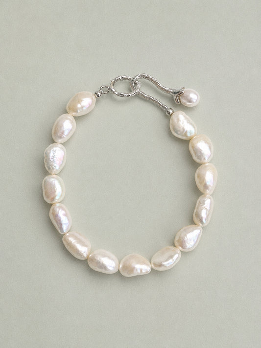Tulia baroque pearl bracelet with irregular white pearls and a silver-tone tulip toggle clasp, shown fastened.