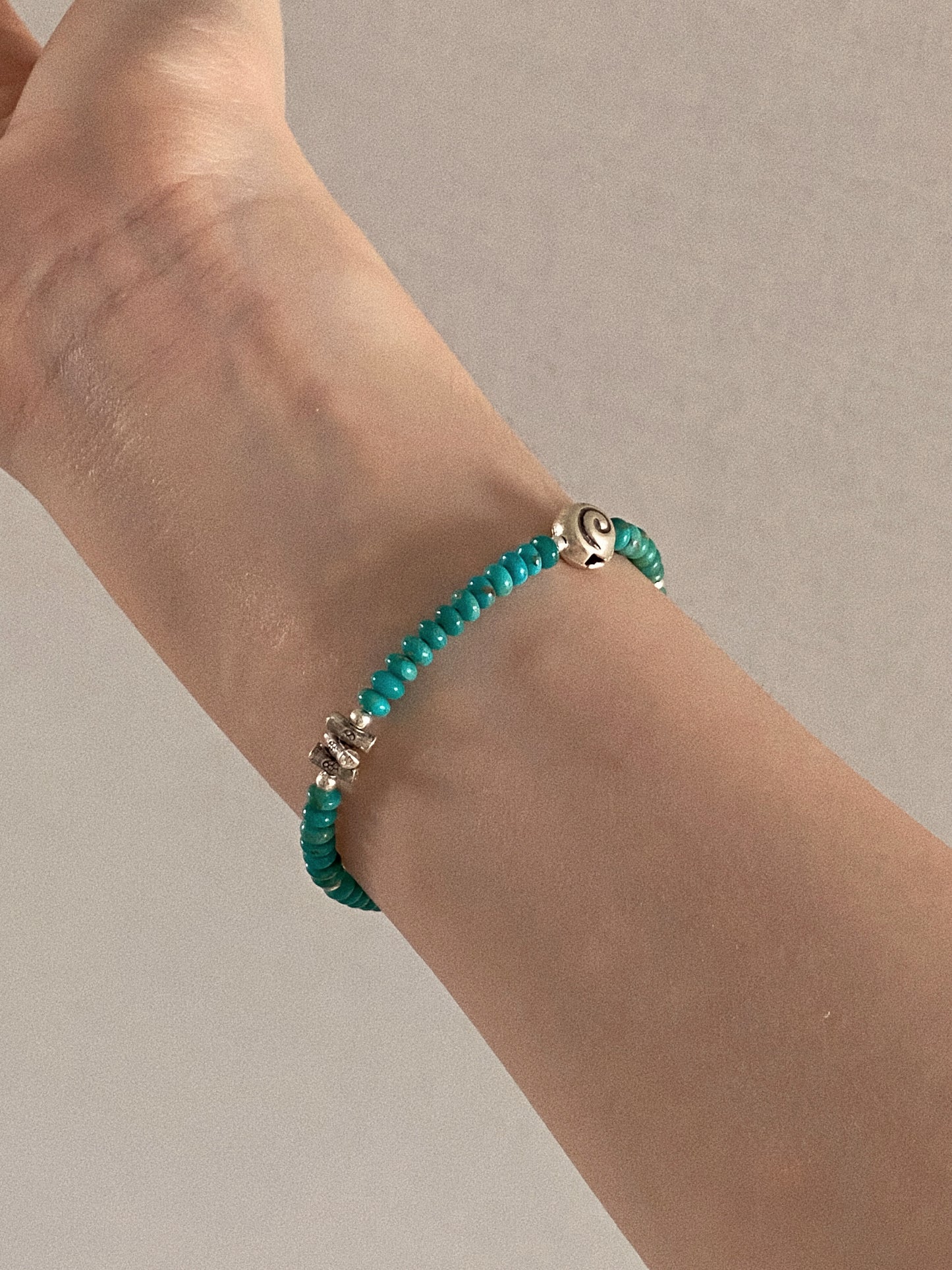 Natural turquoise beaded bracelet worn on the wrist showing the silver spiral and flower beads