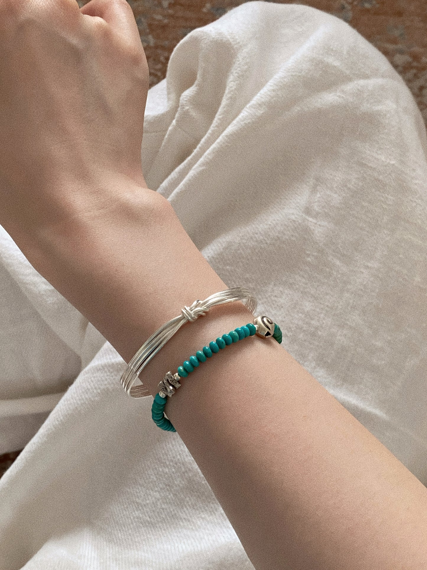 Wrist stack styling with the turquoise beaded bracelet layered beside a multi strand silver bangle