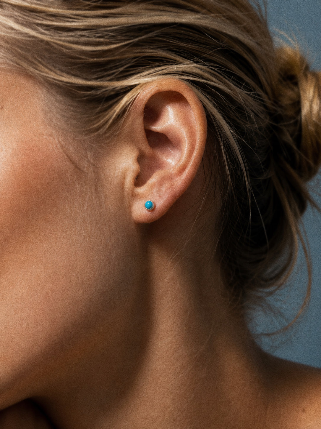 Dream turquoise stud earring in the lobe, a tiny sky blue dot in sterling silver sized for lobes and cartilage alike.