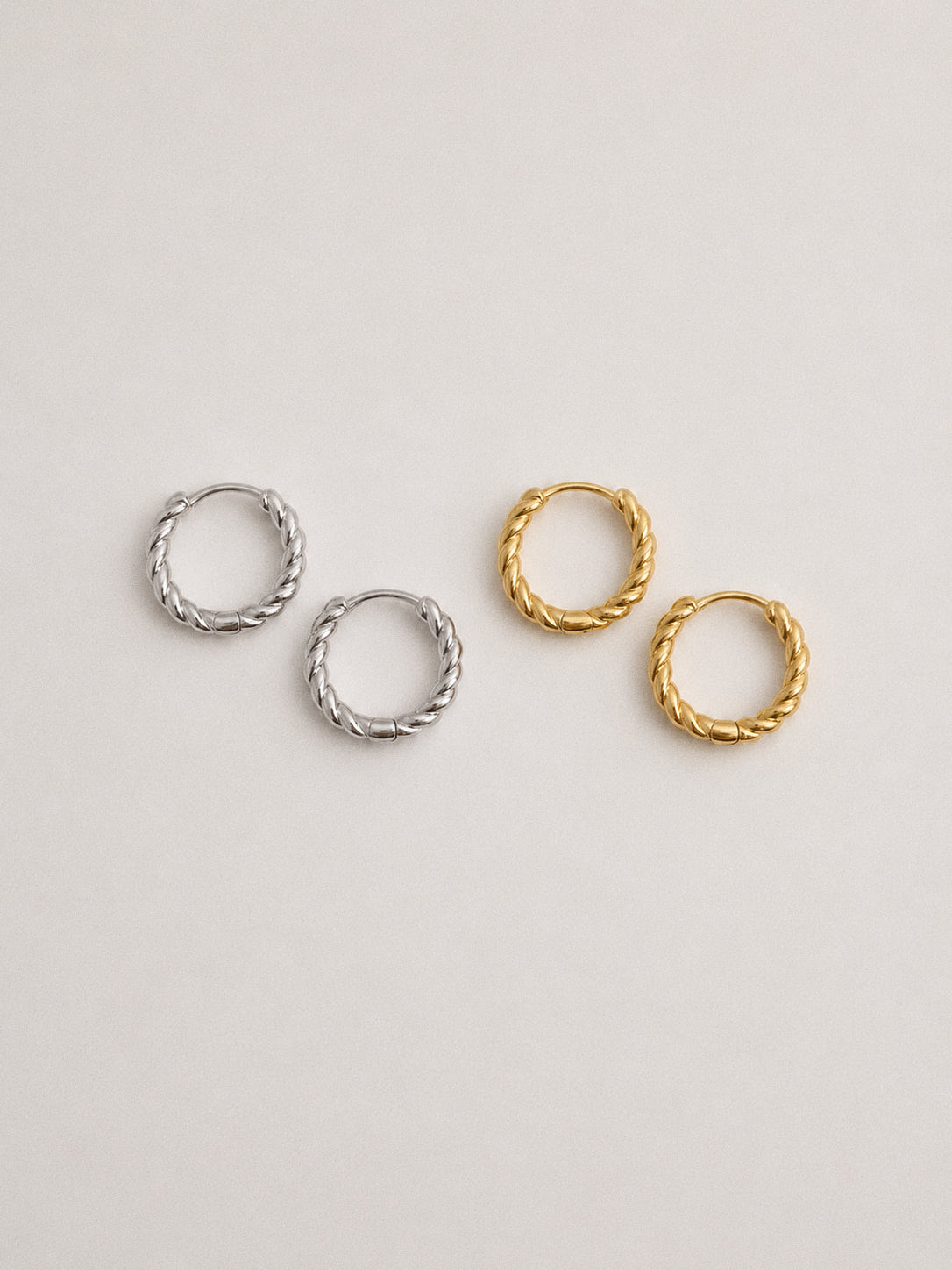 Silver and gold twisted rope huggie hoop earrings shown side by side, 925 sterling silver hoops in both finishes