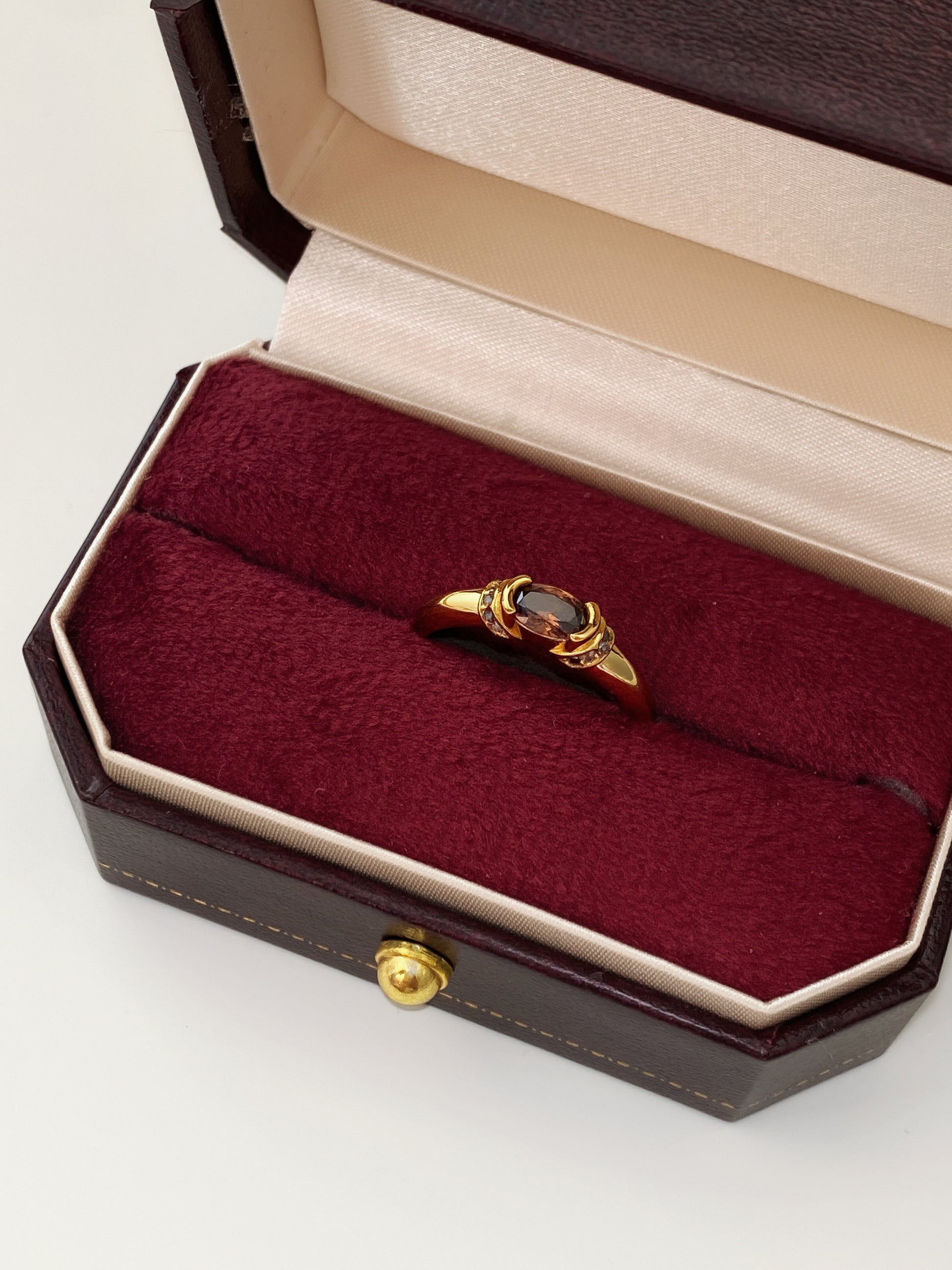 A gold smokey quartz ring presented in a luxury deep red velvet-lined jewellery box.
