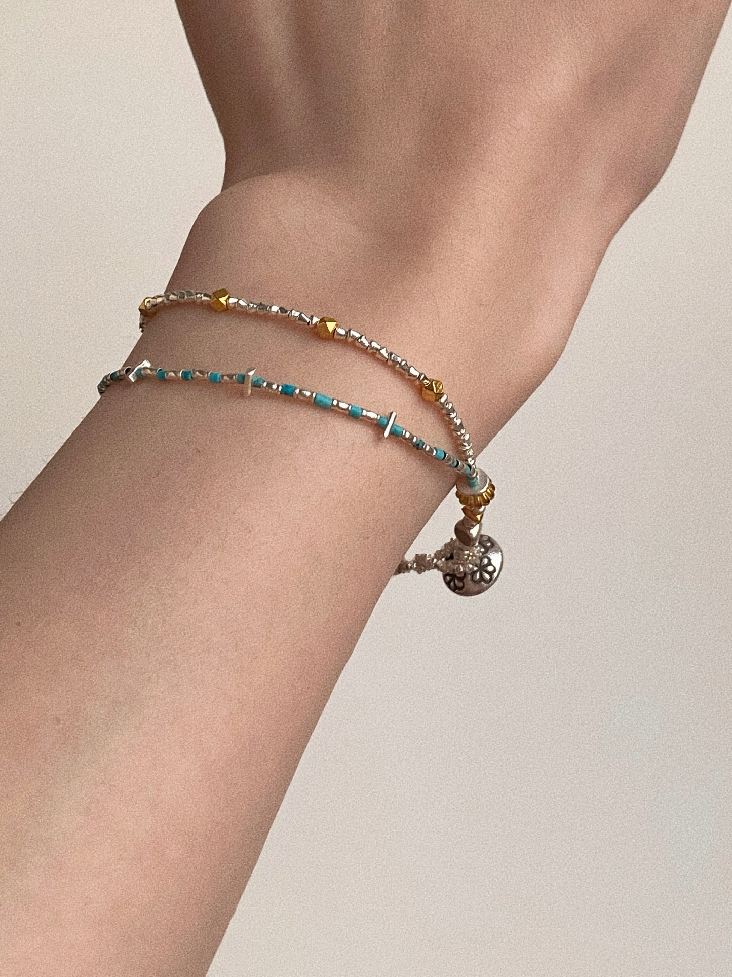 On-wrist styling of Wanderlust turquoise bracelet with hand-stamped Thai silver flower charm by Deja Vu Jewellery