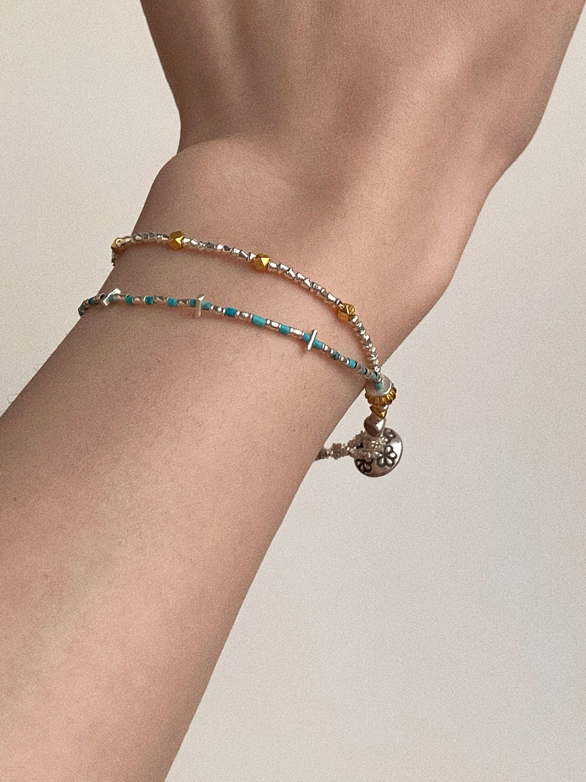 On-wrist styling of Wanderlust turquoise bracelet with hand-stamped Thai silver flower charm by Deja Vu Jewellery