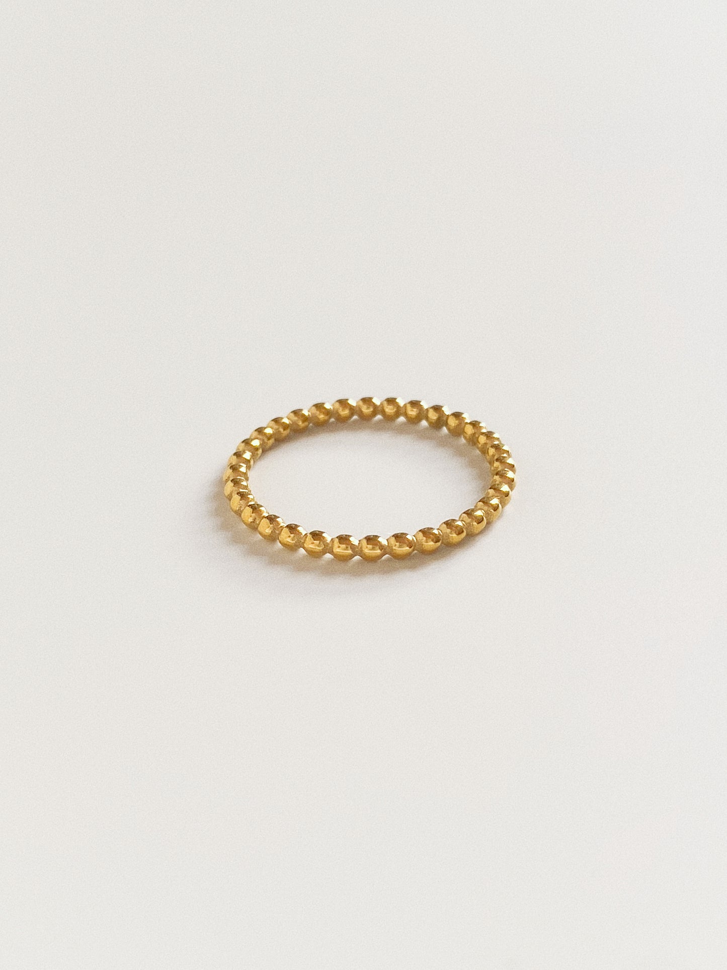 A delicate narrow gold round bead ring, 100% waterproof and gym-proof.