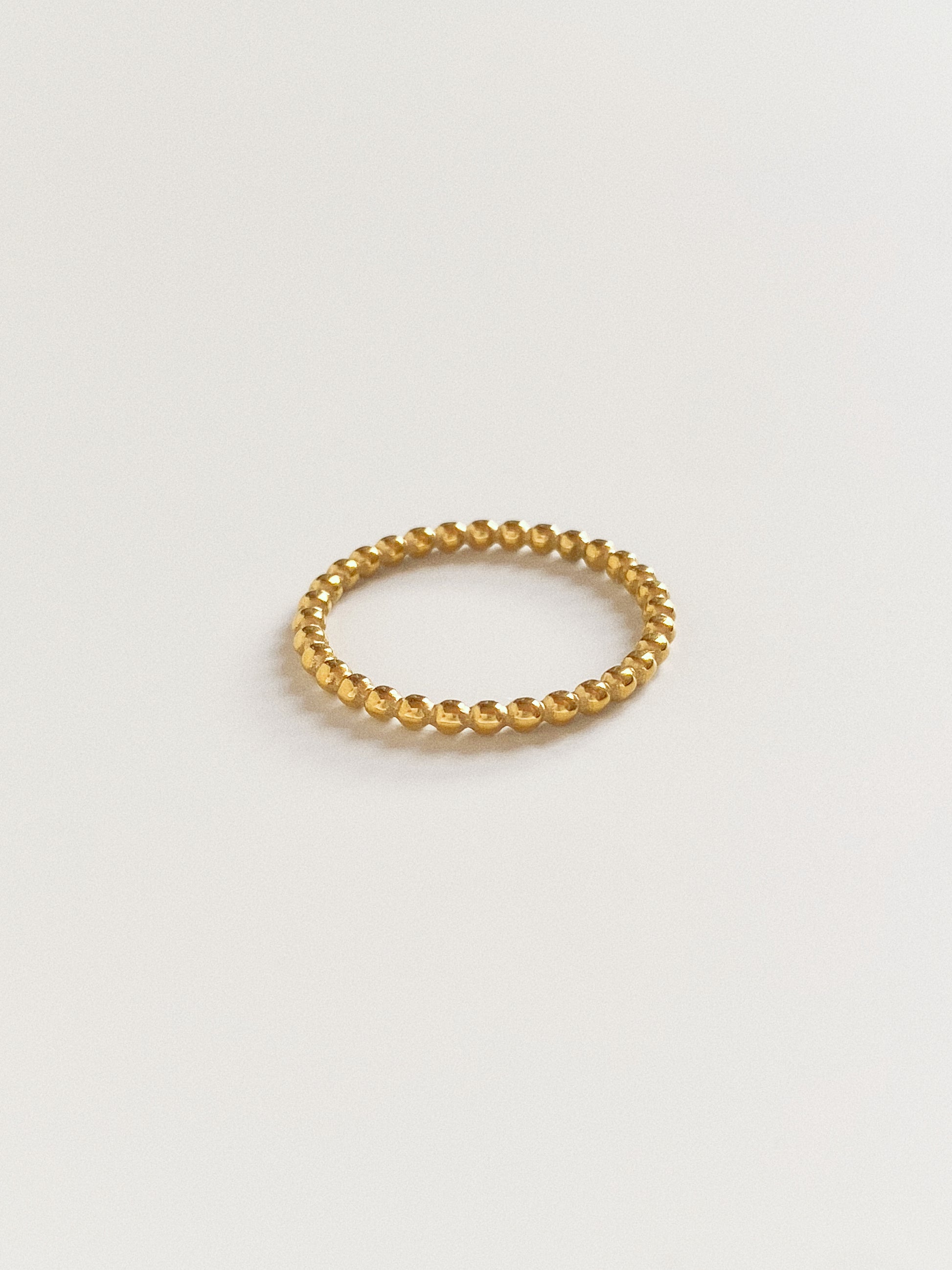 A delicate narrow gold round bead ring, 100% waterproof and gym-proof.