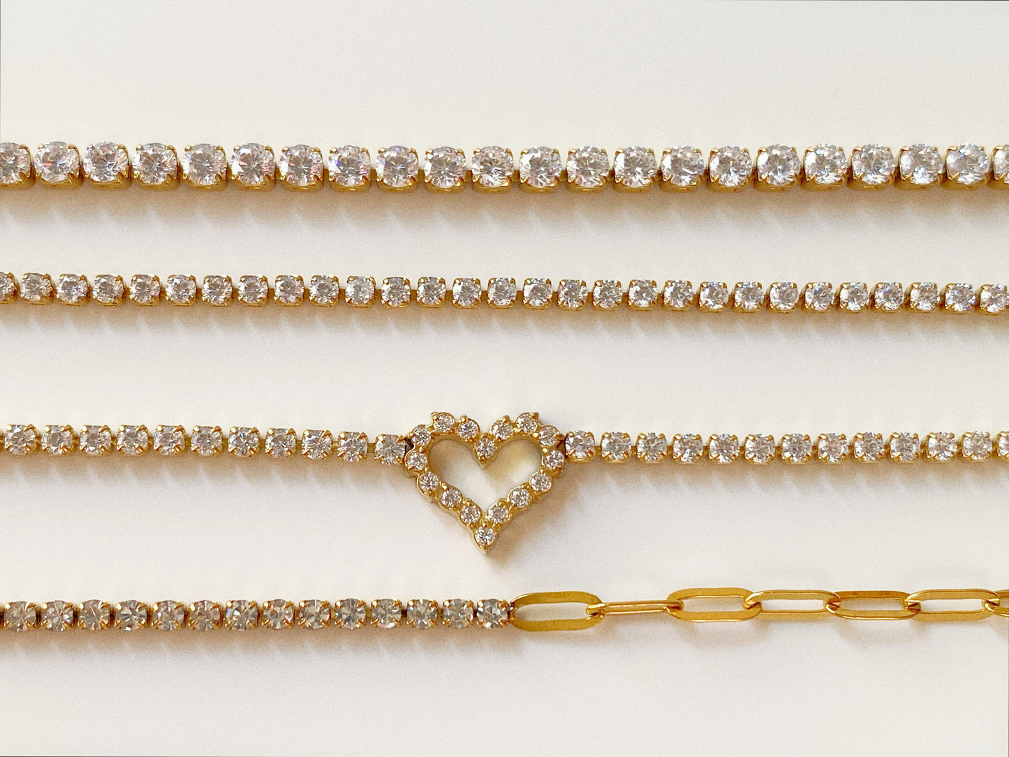 Comparison of waterproof gold tennis bracelet styles including classic, dainty, heart and paperclip versions by Deja Vu Jewellery