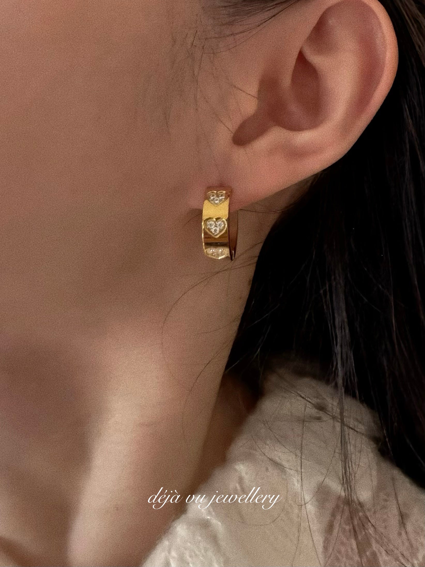 Model wearing The Amore Wide Hoops, showing the 0.6cm thick gold band and crystal heart details on the ear.