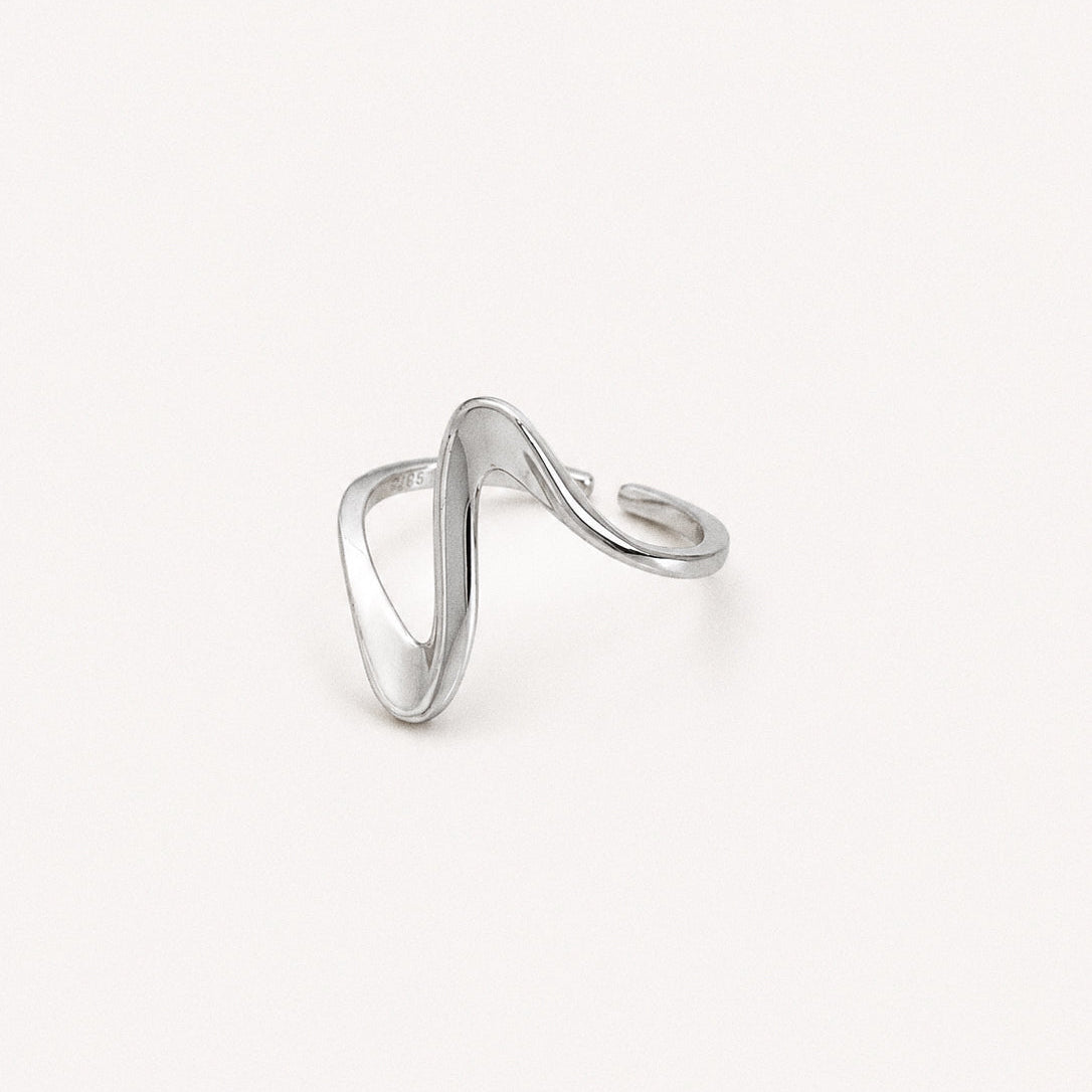 Wavy open ring in polished silver with a fluid curved band photographed on a neutral background