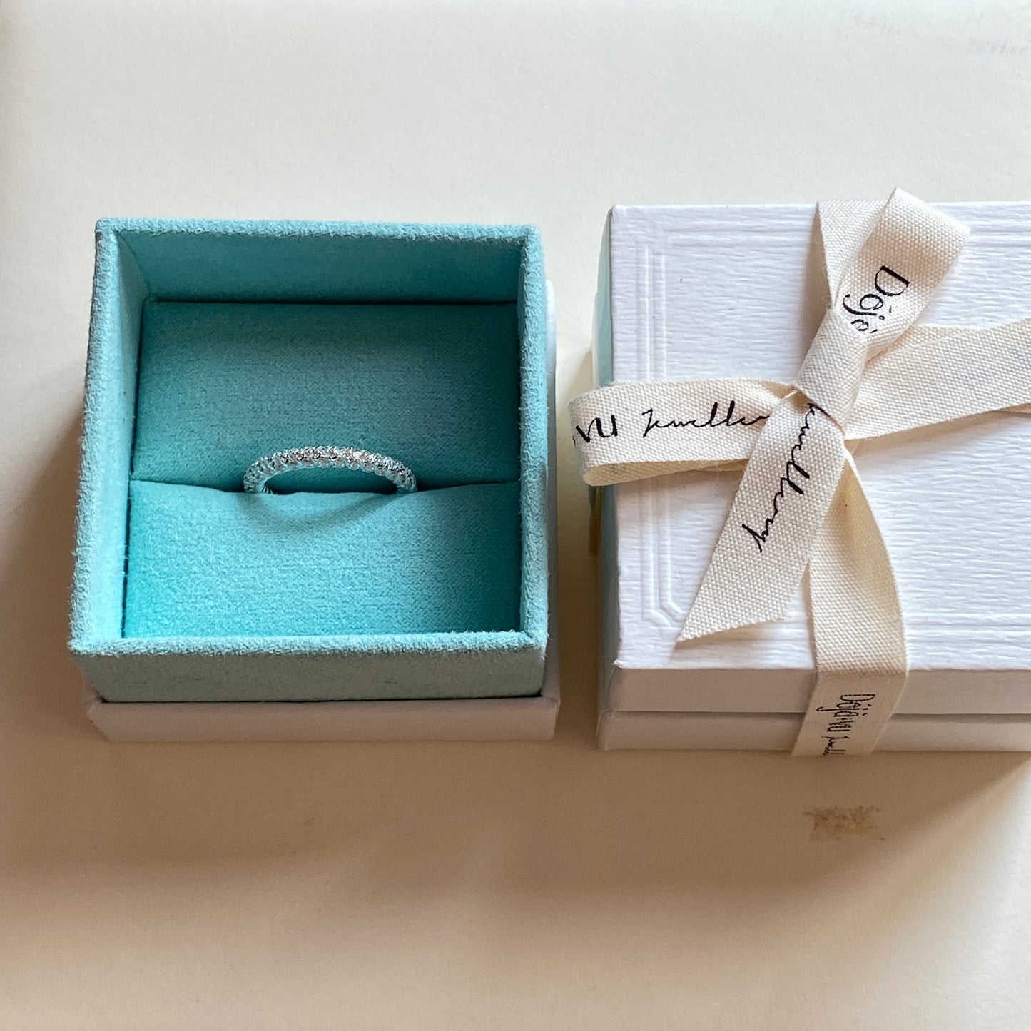 Dainty minimalist sterling silver ring presented in a blue jewelry box and white ribboned gift box.