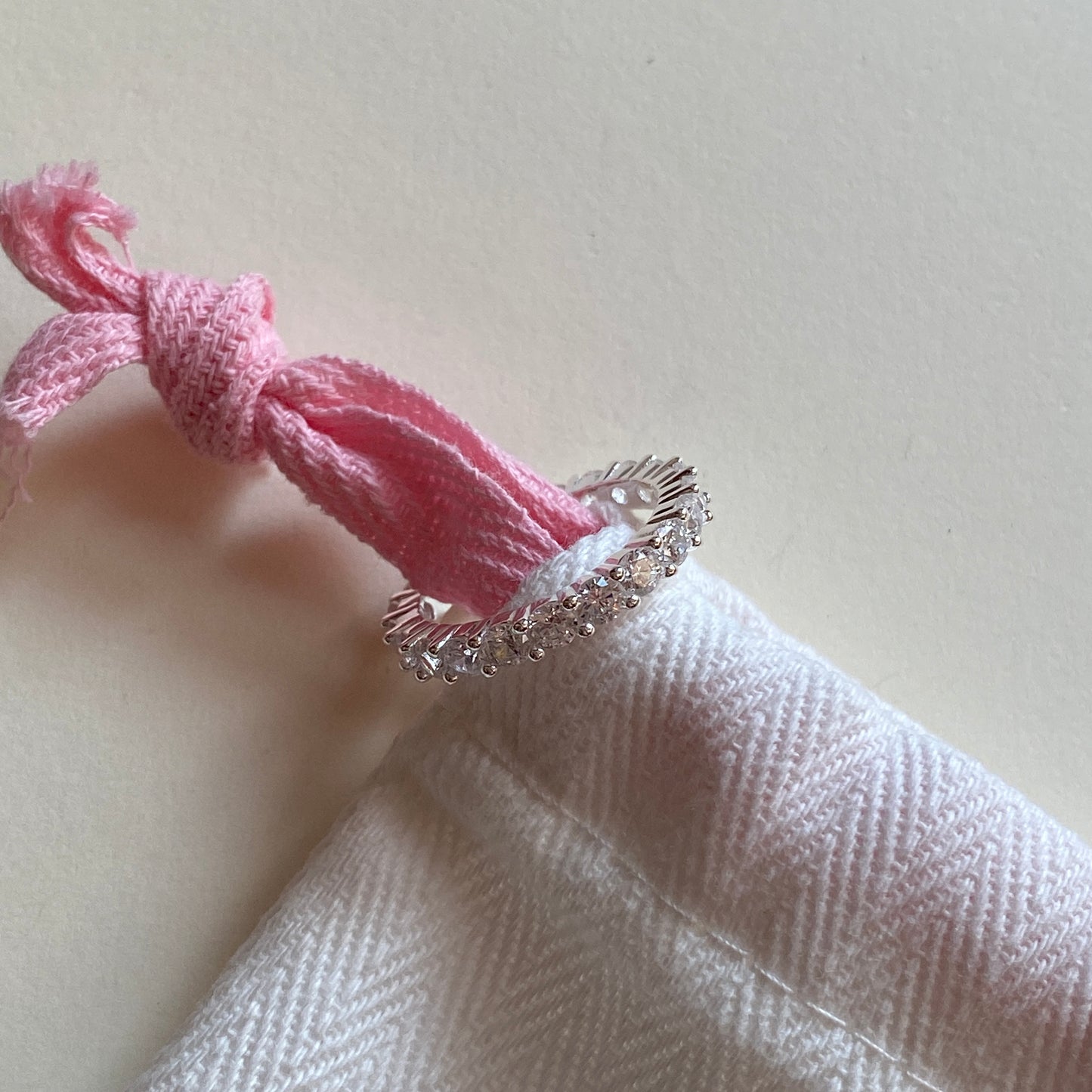 Single sterling silver wedding band resting on soft pouch.