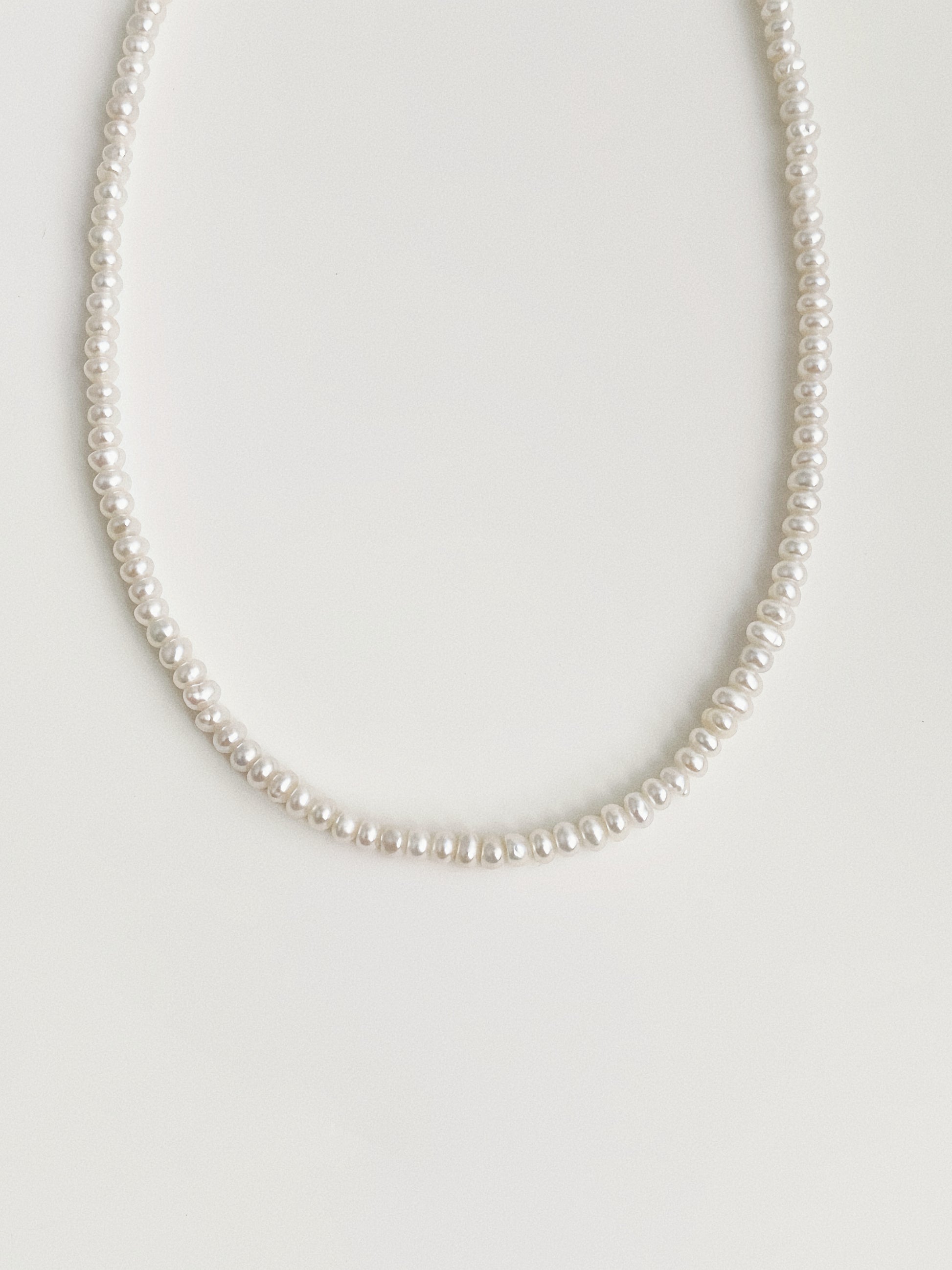 Whisper dainty freshwater pearl necklace laid flat showing full strand of tiny button pearls