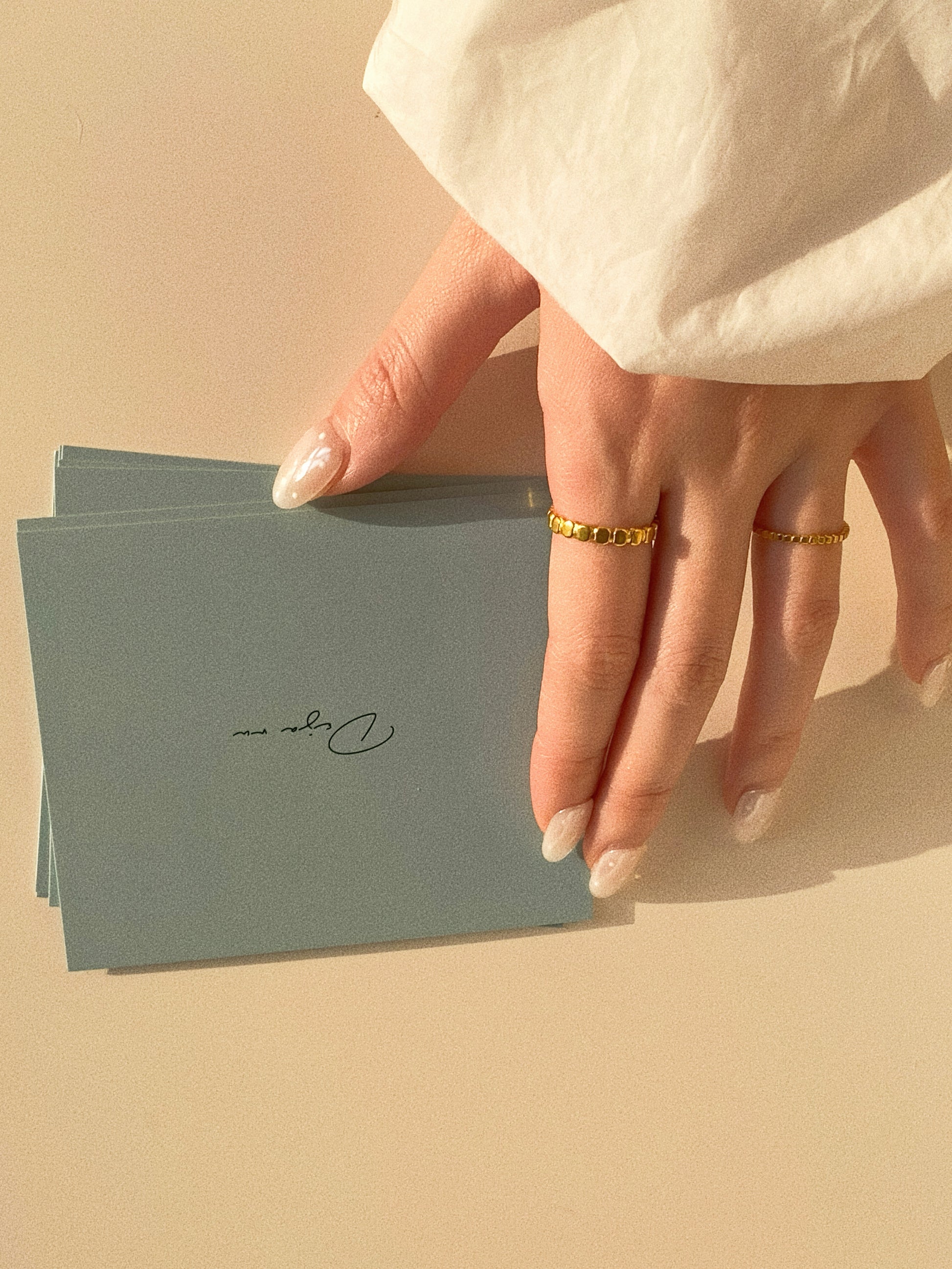 Close-up of the wide and narrow beaded gold rings worn on fingers, highlighting the polished finish and texture.