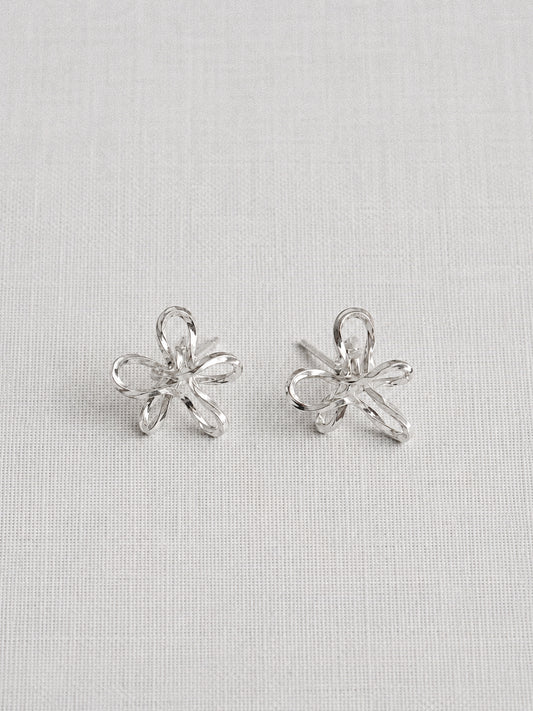 Handmade sterling silver wire flower stud earrings with looped petal design on a linen background by Deja Vu