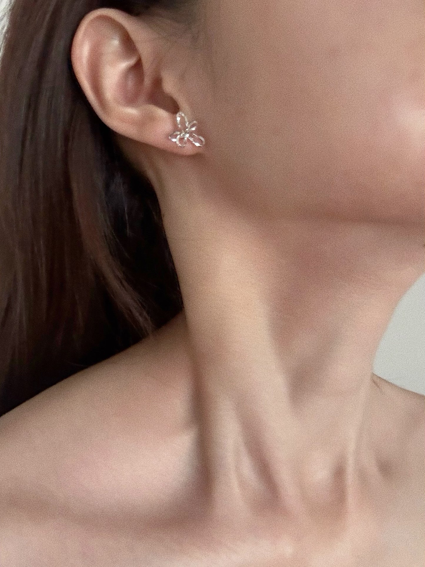 Sterling silver wire flower stud earrings worn on model showing 13mm by 14mm sculptural floral silhouette
