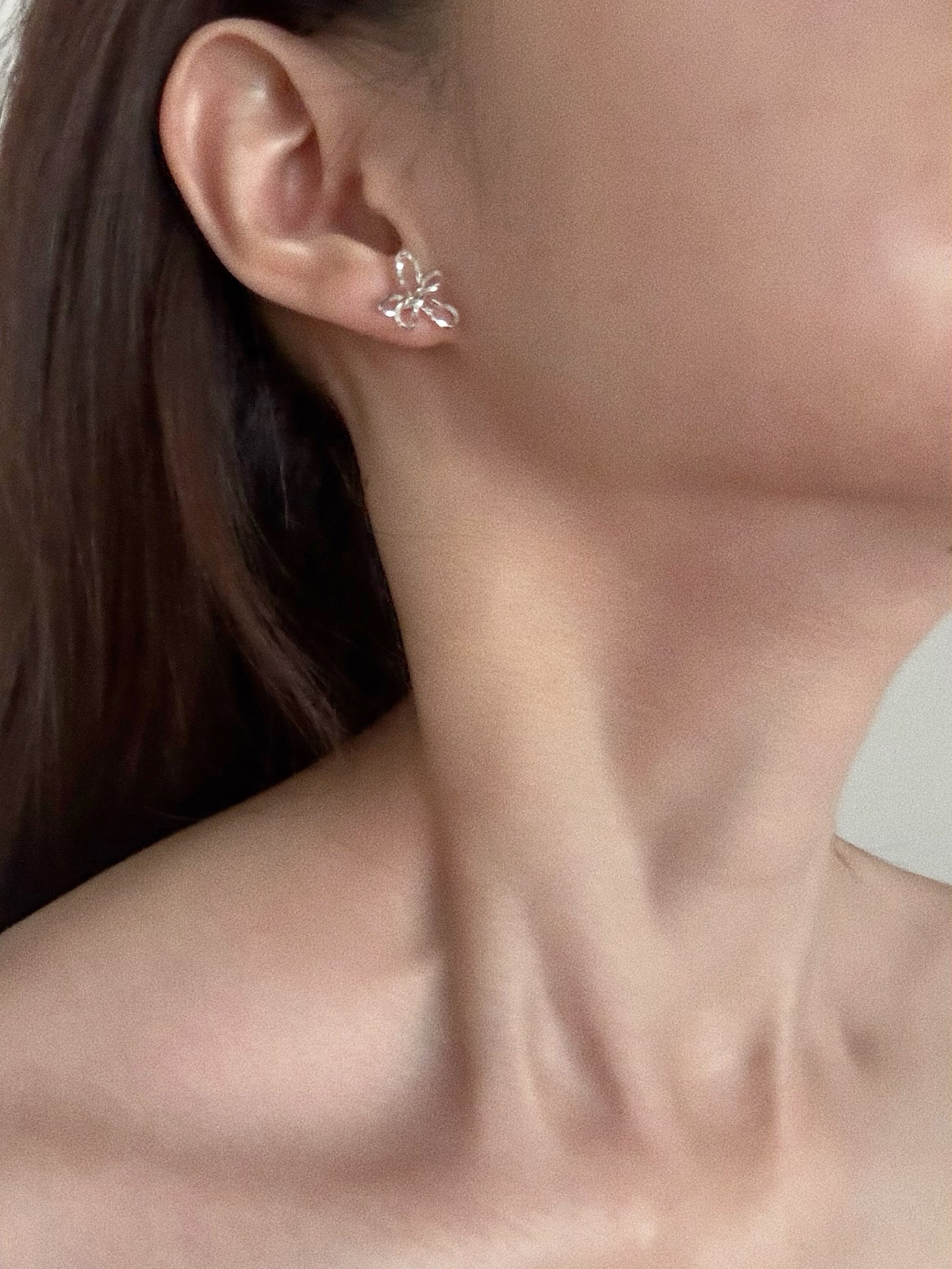 Sterling silver wire flower stud earrings worn on model showing 13mm by 14mm sculptural floral silhouette